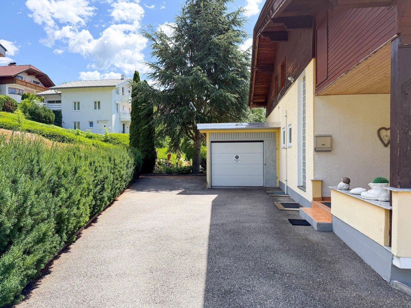 Zufahrt zum Haus mit separater Garage und gepflegter Hecke.