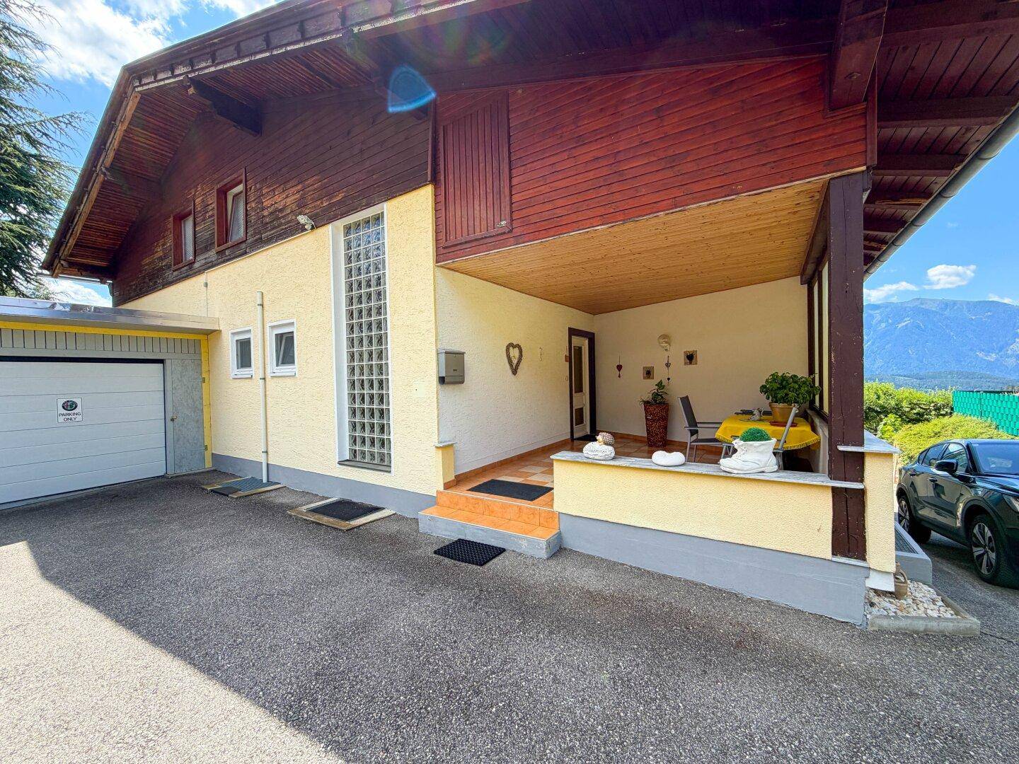 Überdachter Hauseingangsbereich mit Glasbausteinwand und Bergblick.