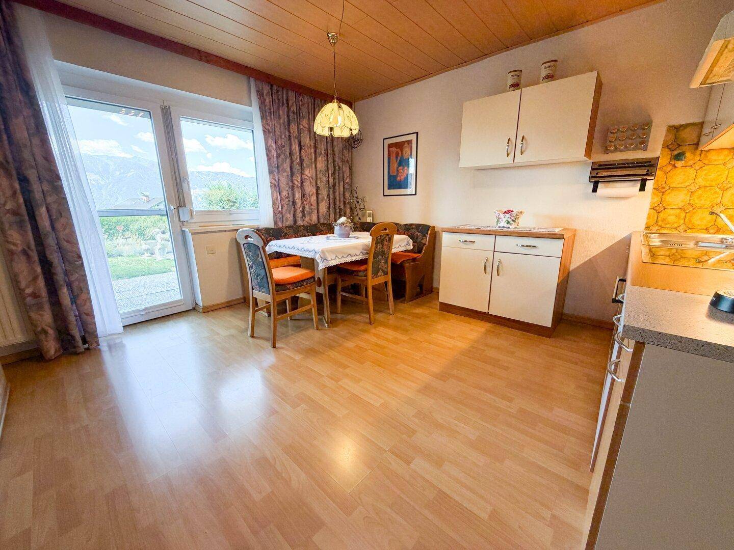 Helle Wohnküche mit Essecke und direktem Zugang zum Garten mit Bergblick.