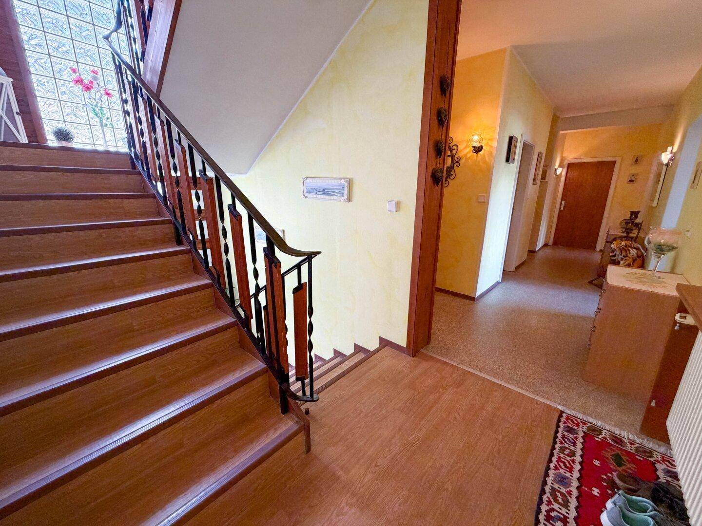 Heller Flur mit Holztreppe und traditionellem Geländer.