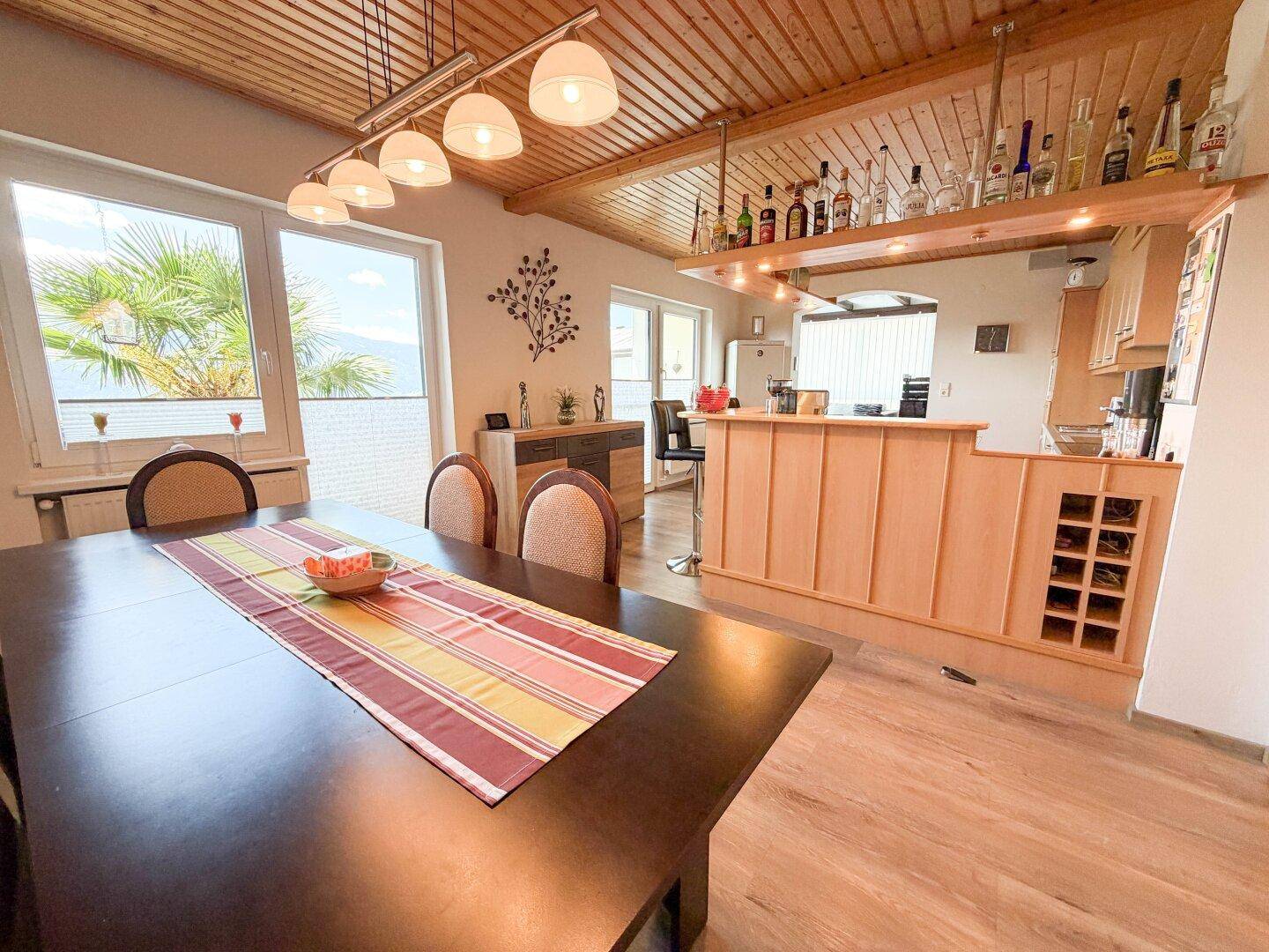 Gemütlicher Essbereich mit Holzbalkendecke, großem Esstisch und integrierter Bar.
