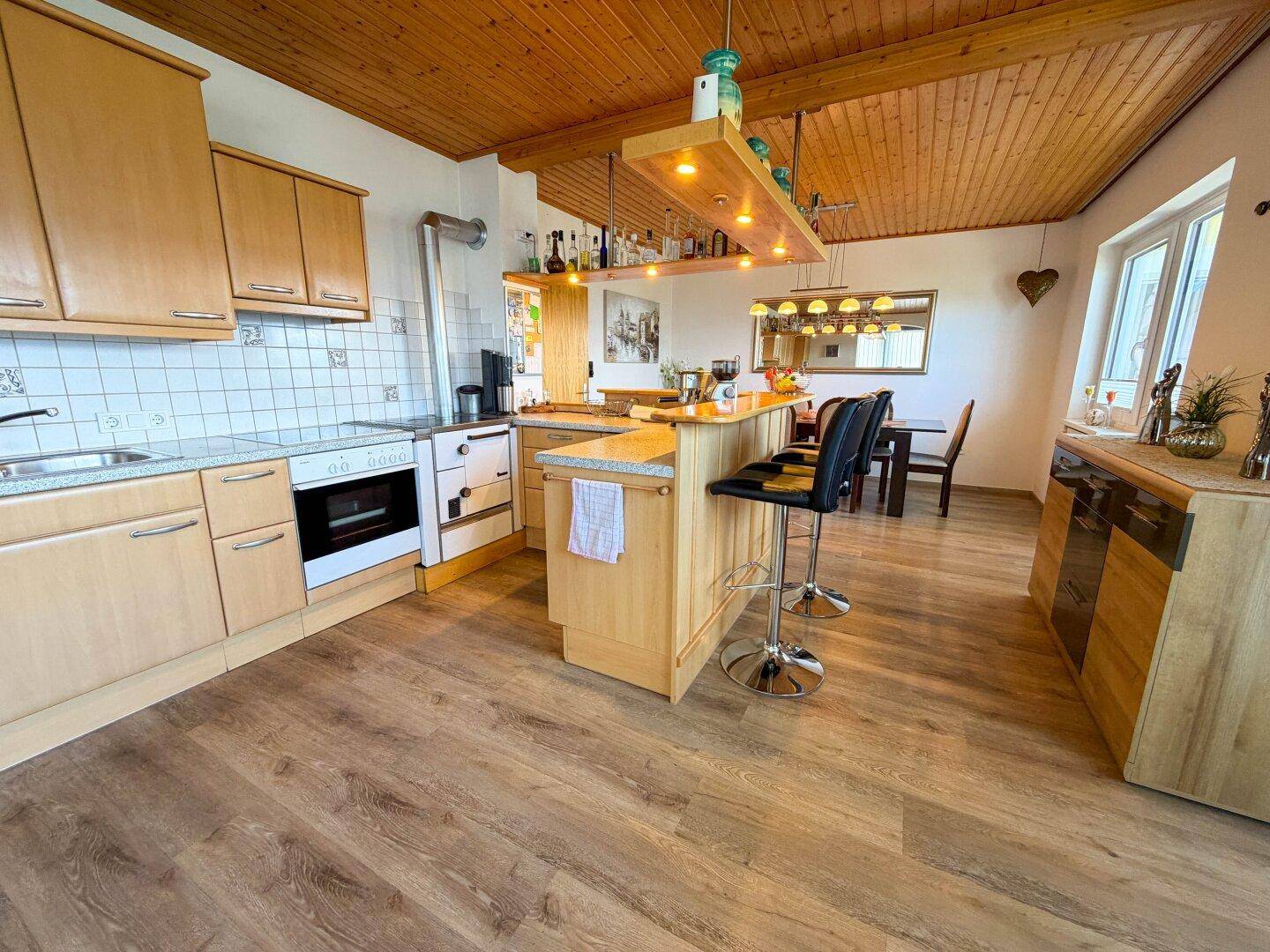 Rustikale Küche mit Holzelementen, Kücheninsel und traditionellem Ofen.