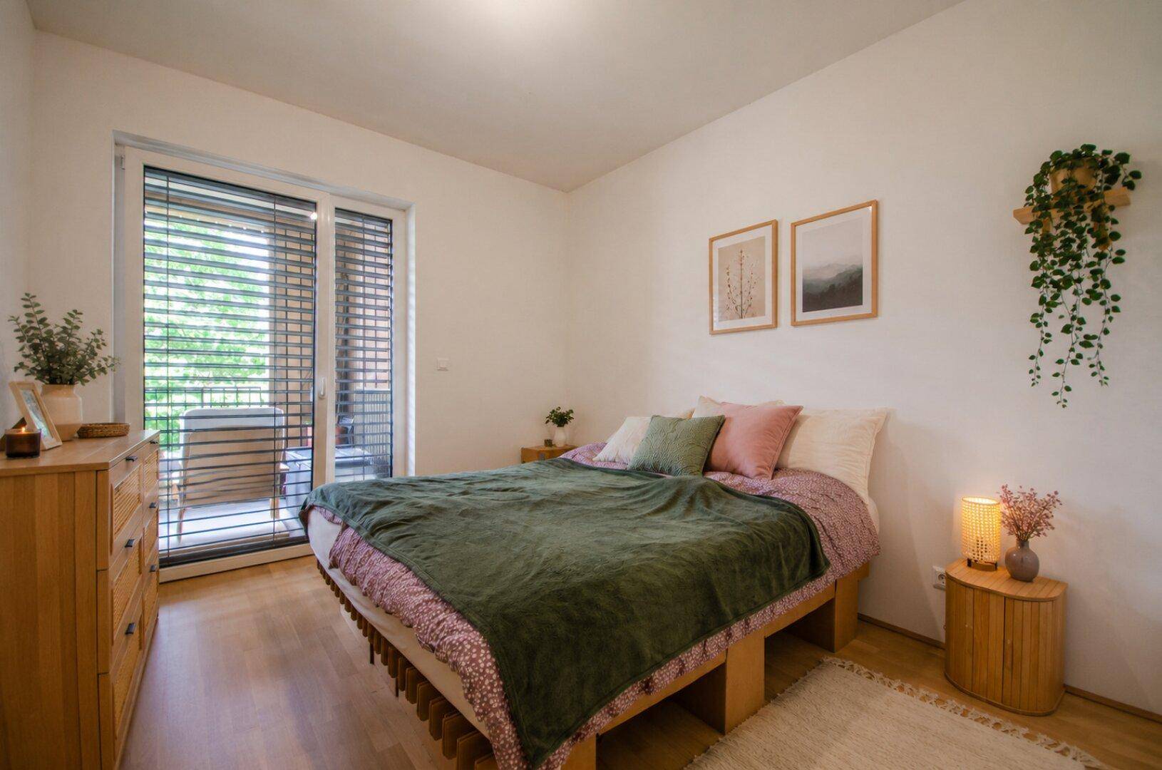 Gemütliches Schlafzimmer mit Holzbett, Nachttischen und Zugang zu einem kleinen Balkon.