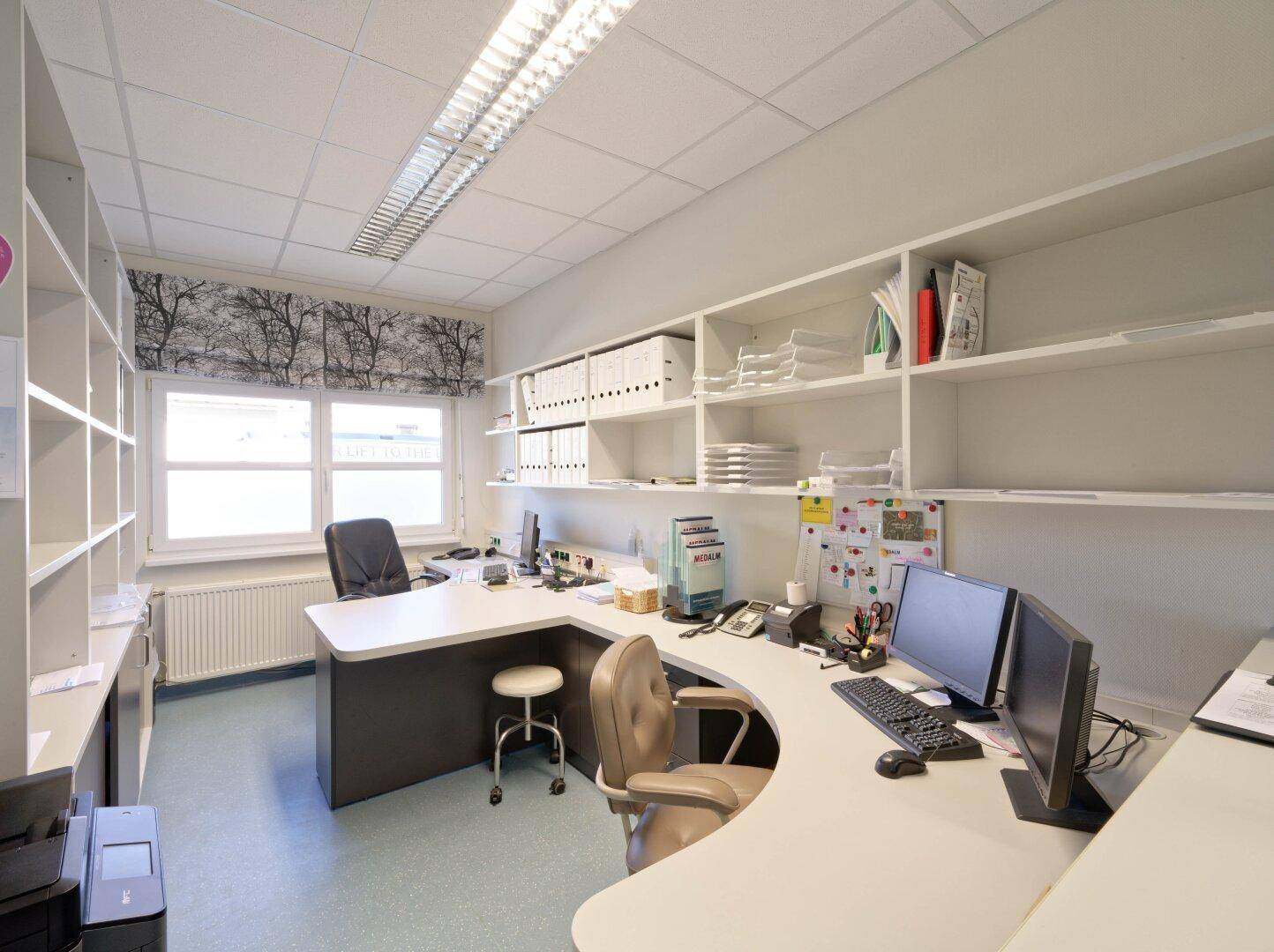 Helles Büro mit großem Empfangstresen, mehreren Computern und vielen Ablagemöglichkeiten.