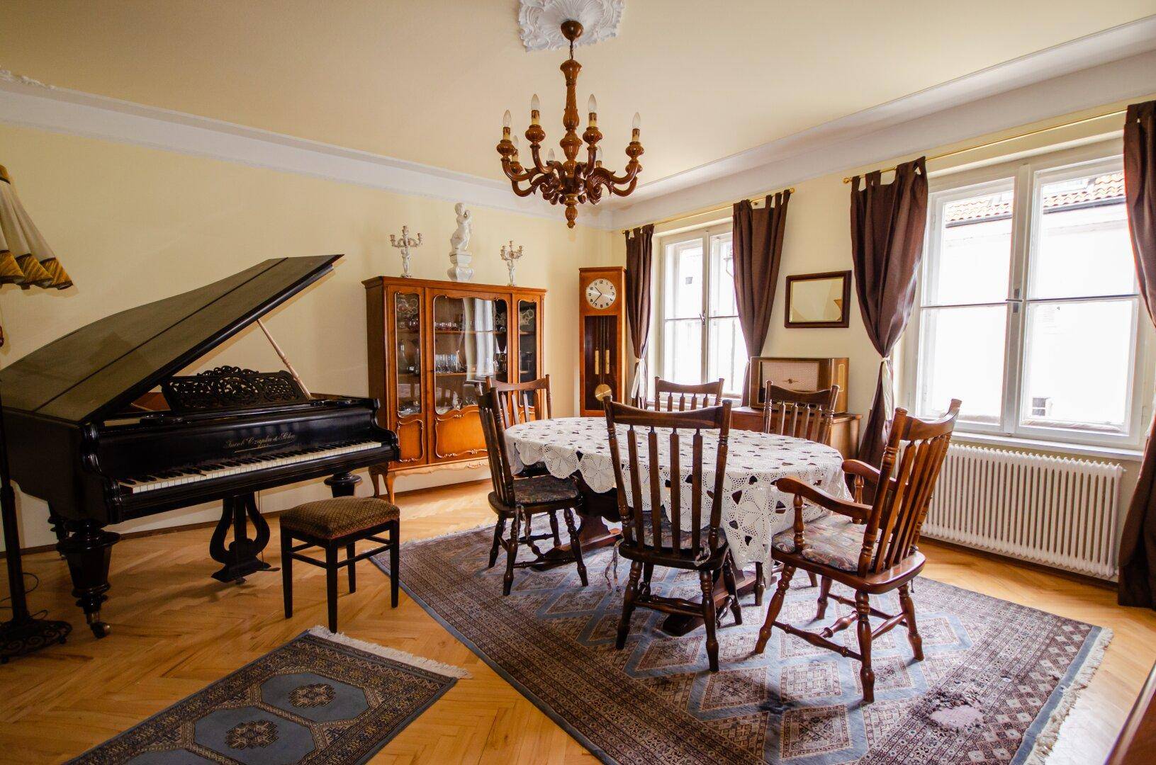 Elegantes Esszimmer mit einem Flügel, großem Esstisch und traditionellen Holzmöbeln.