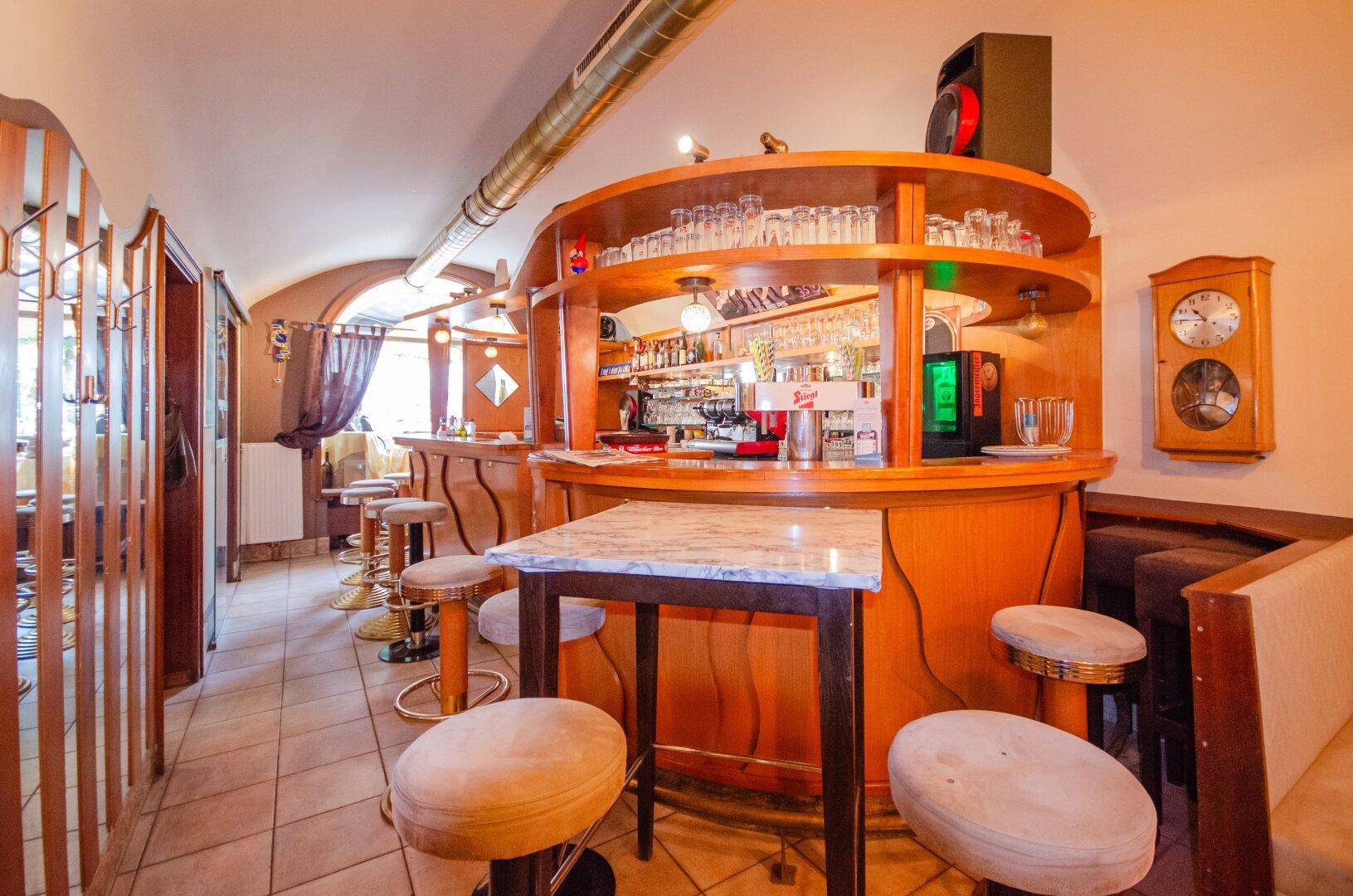 Gemütliche Bar mit runder Holztheke, Hockern und gefliestem Boden in einem traditionellen Stil.
