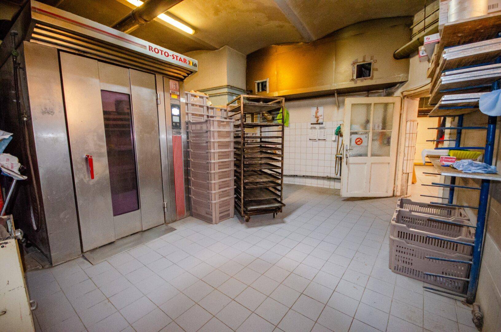 Große Bäckereiküche mit industriellen Öfen und Regalen für Backbleche.