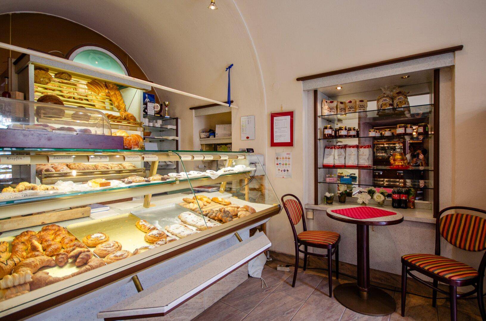 Bäckerei mit Auslagen voller Gebäck und einem kleinen Sitzbereich für Kunden.