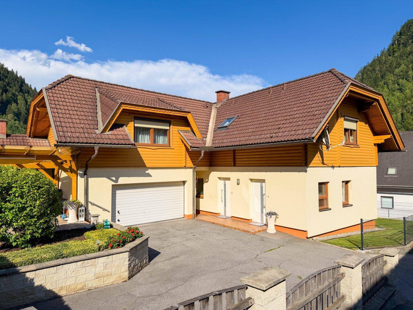 Vorderansicht des Hauses mit integrierter Garage, breiter Zufahrt und traditionellem Satteldach.