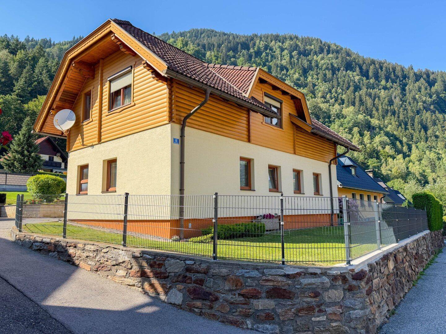 Ansicht des Hauses mit traditioneller Holzverkleidung, Satteldach und gepflegtem Vorgarten in Hanglage.