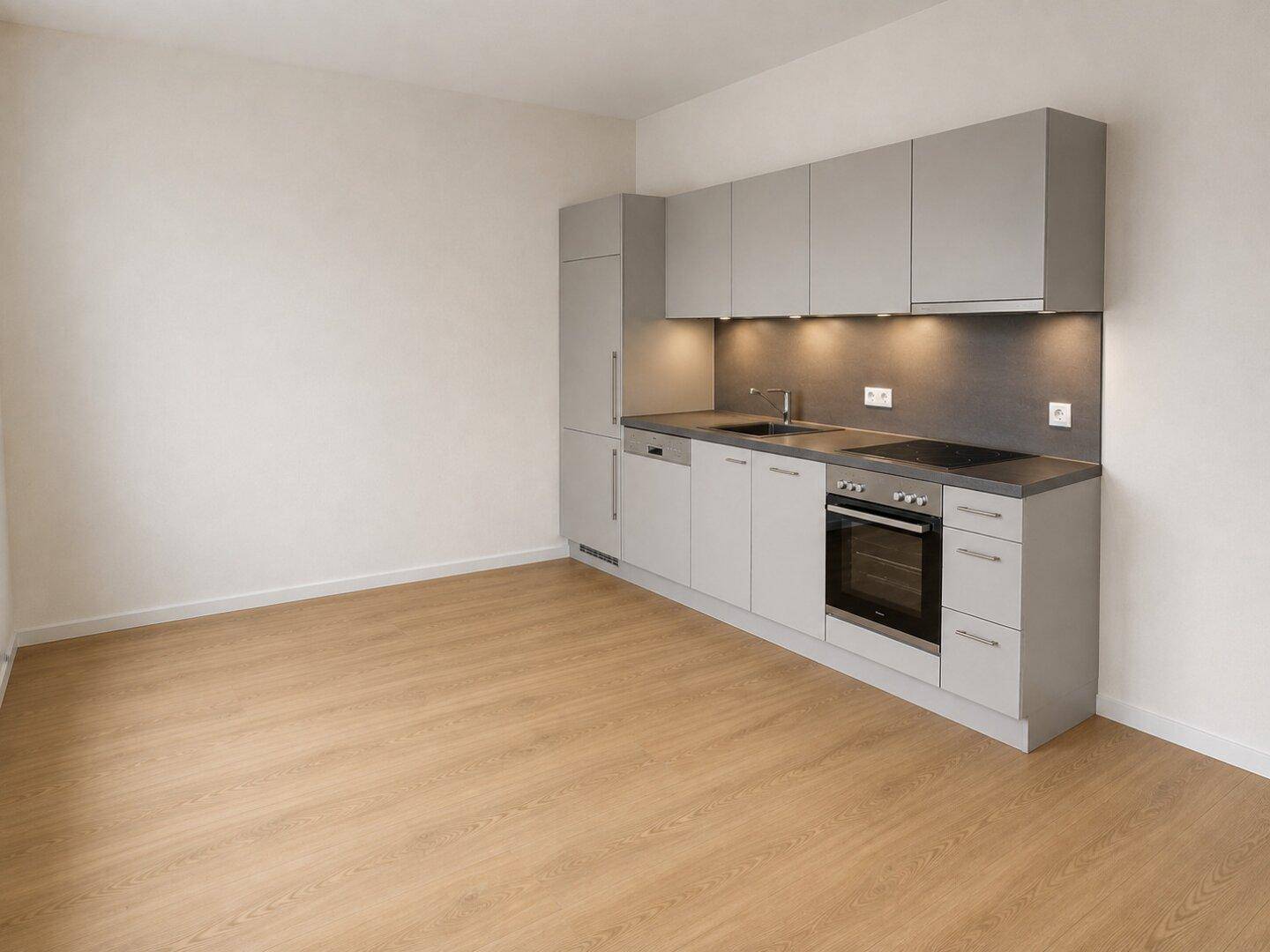 Moderne Küchenzeile mit grauen Schränken, integrierten Geräten und hellem Laminatboden.