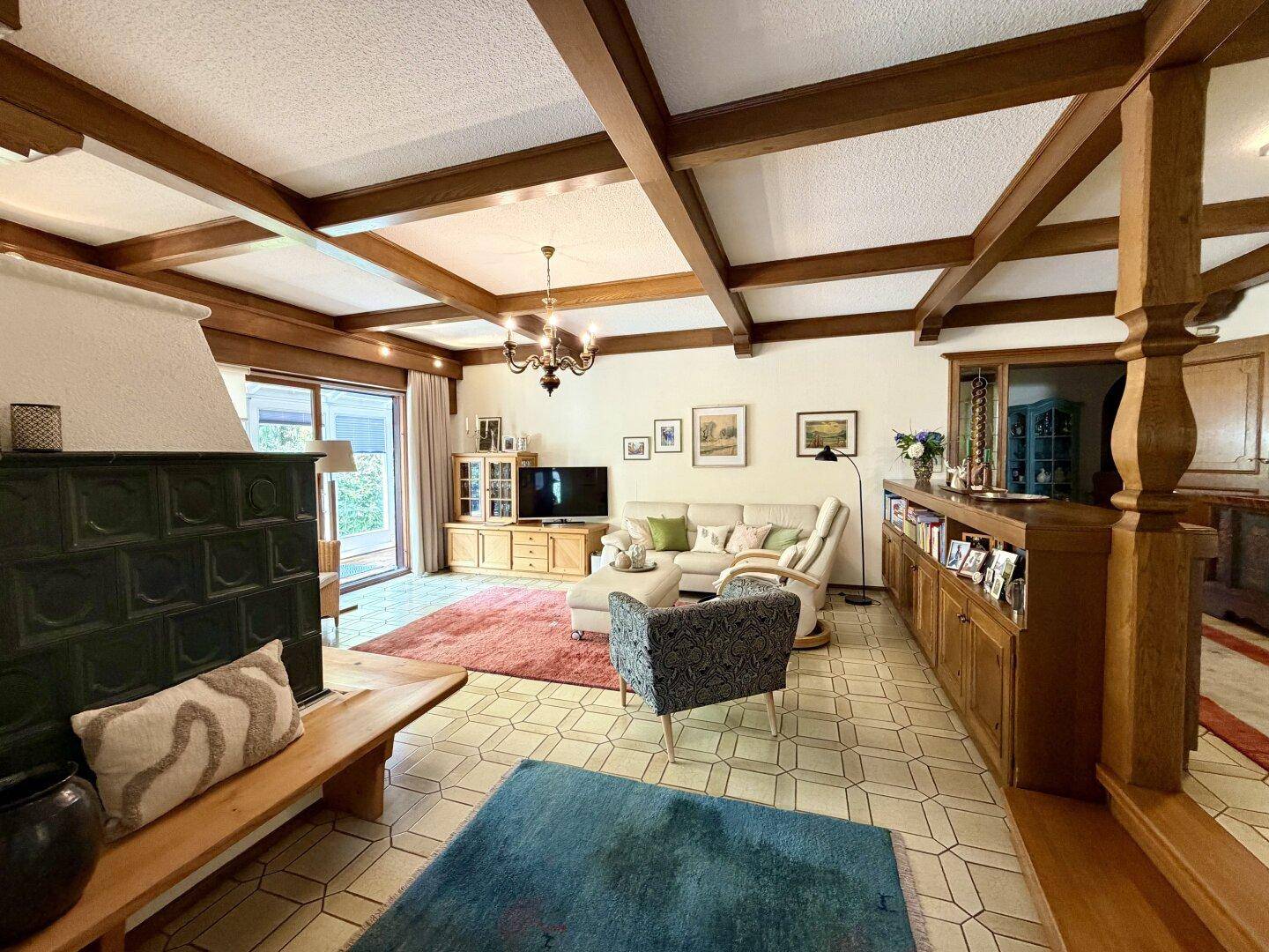 Geräumiges Wohnzimmer mit Holzbalkendecke, Fliesenboden und traditionellen Möbeln.