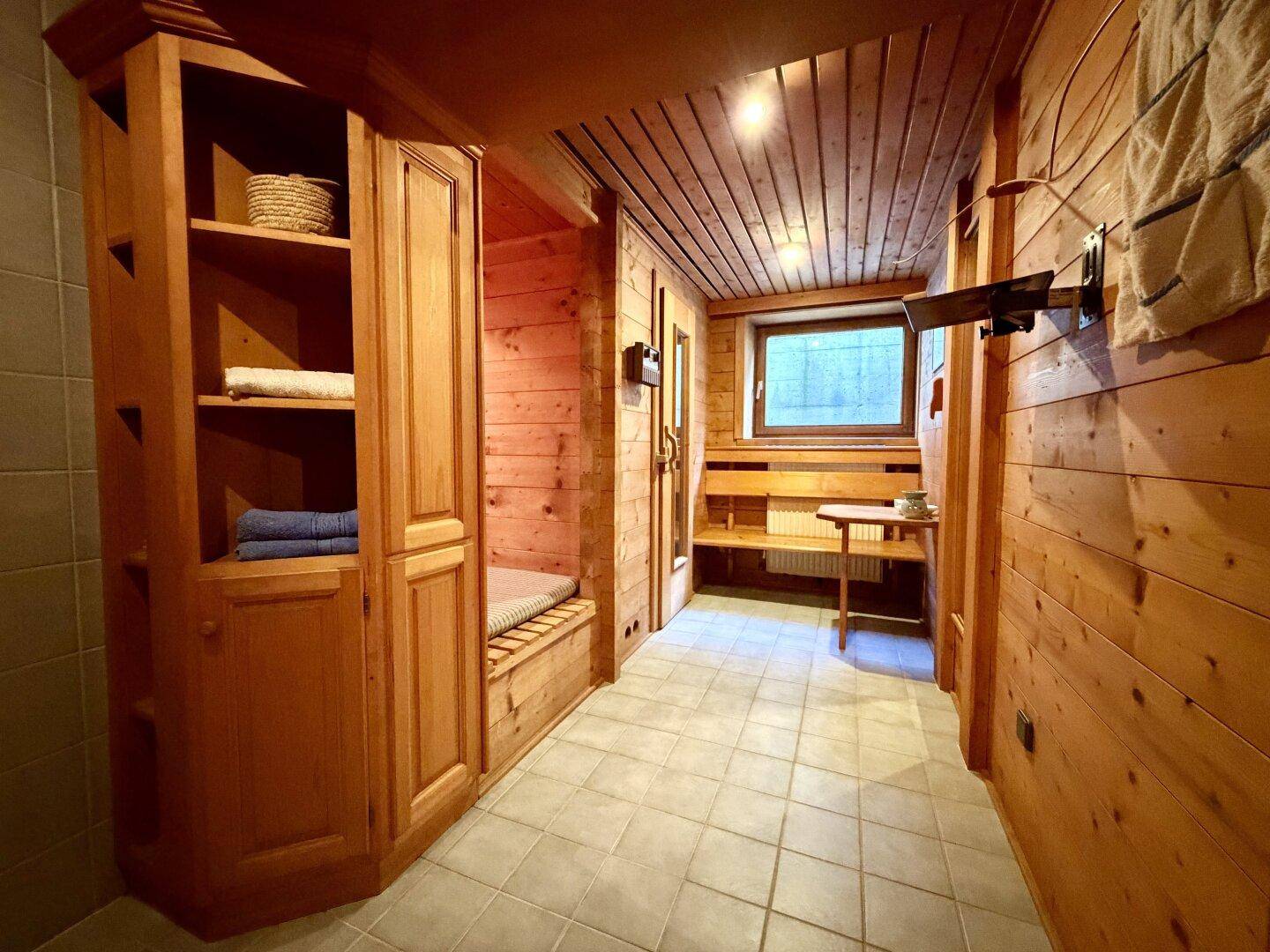 Gemütlicher Wellnessbereich mit Holzverkleidung, Sitzbänken und Fenster.
