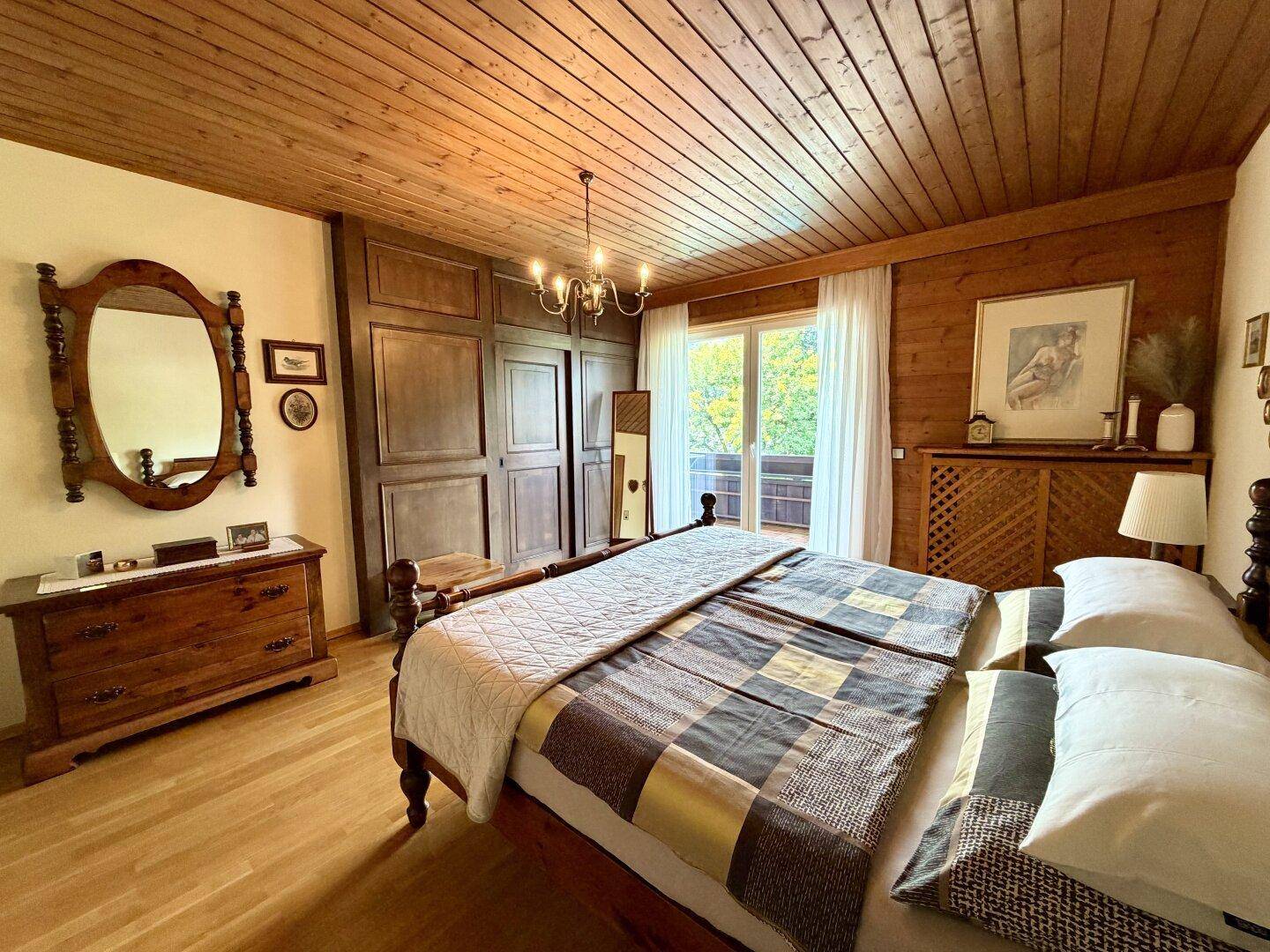 Geräumiges Schlafzimmer mit Holzboden, Holzdecke und traditionellen Möbeln.