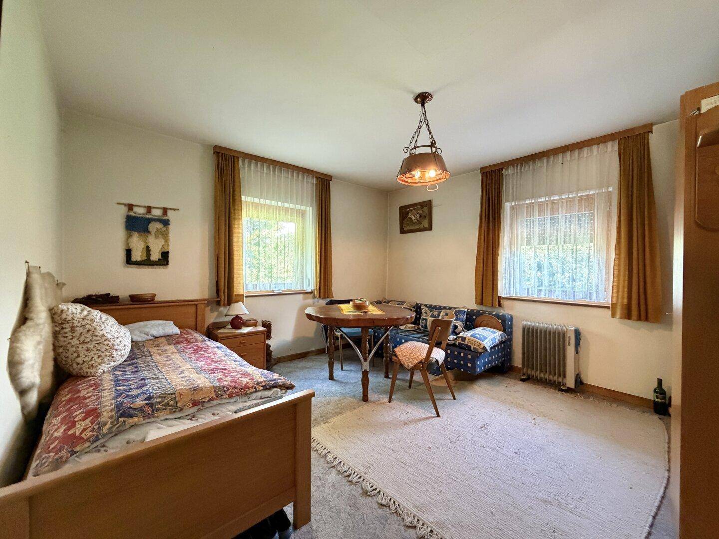Gemütliches Schlafzimmer mit Einzelbett, kleinem Esstisch und traditioneller Einrichtung.