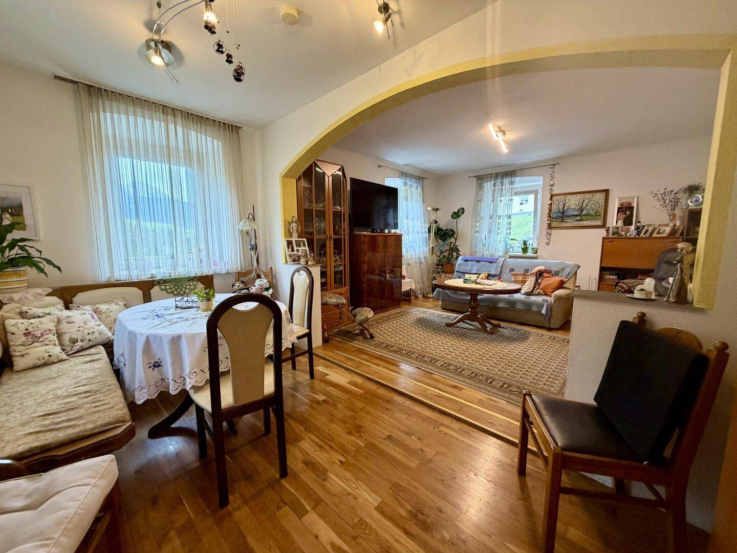 Geräumiger Wohn- und Essbereich mit Holzboden, großen Fenstern und traditioneller Einrichtung.