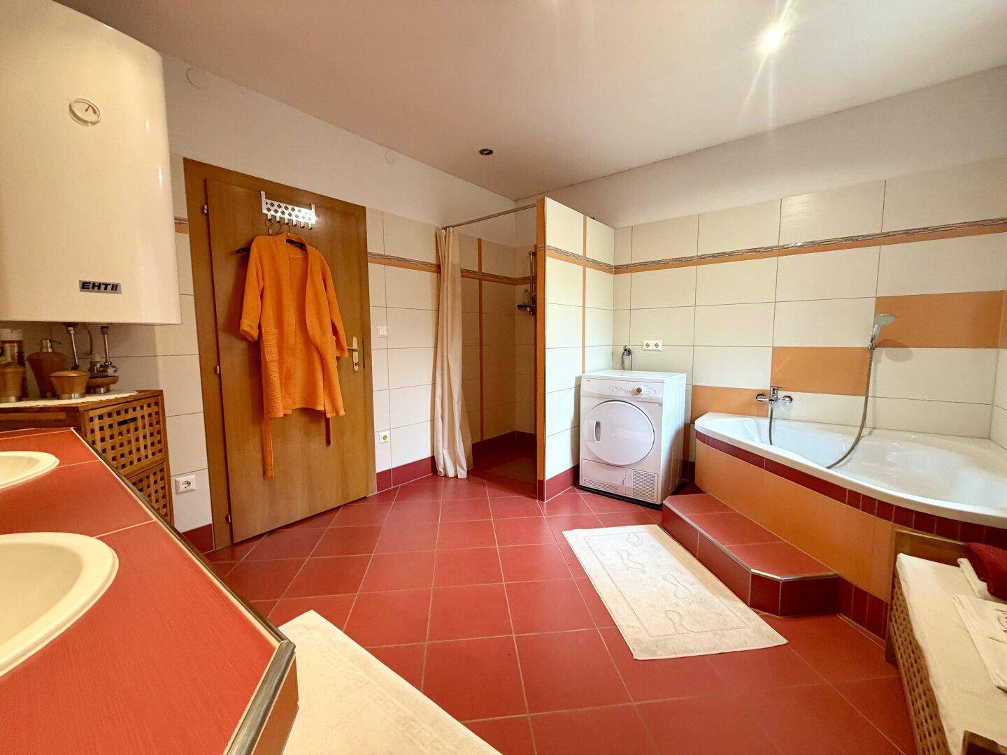 Geräumiges Badezimmer mit Badewanne, Dusche, Doppelwaschbecken und farbigen Fliesen.