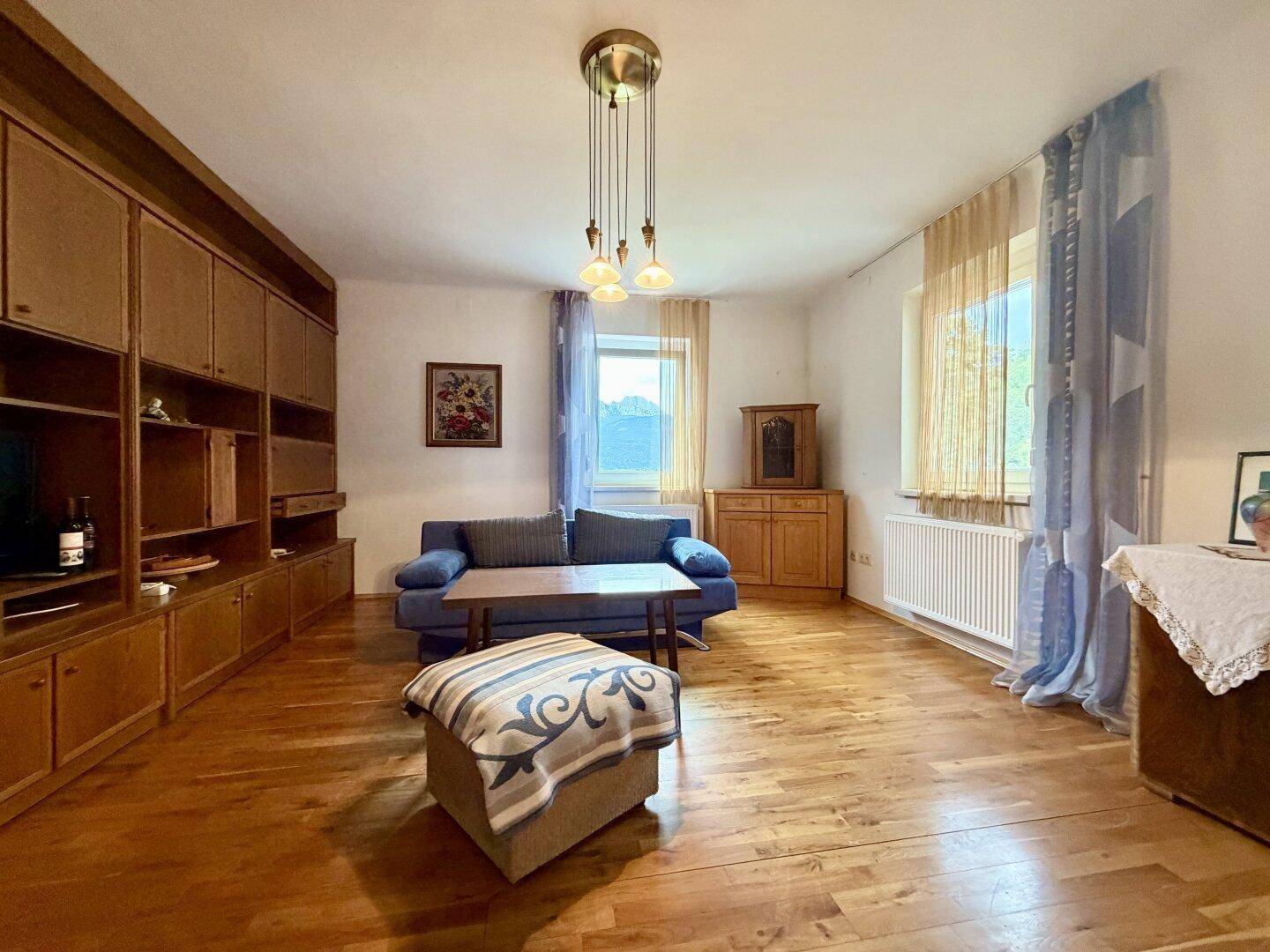 Gemütliches Wohnzimmer mit Holzboden, großem Wandschrank und bequemer Couch.