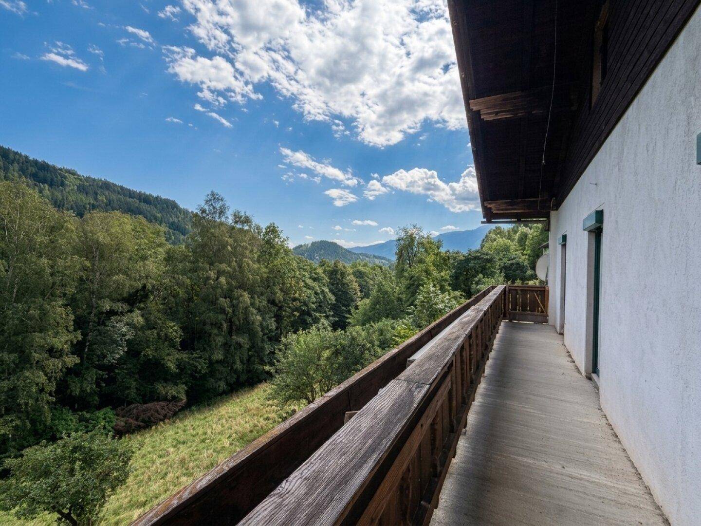 Langer Balkon mit Holzgeländer und weitem Blick auf die umliegende Berglandschaft.