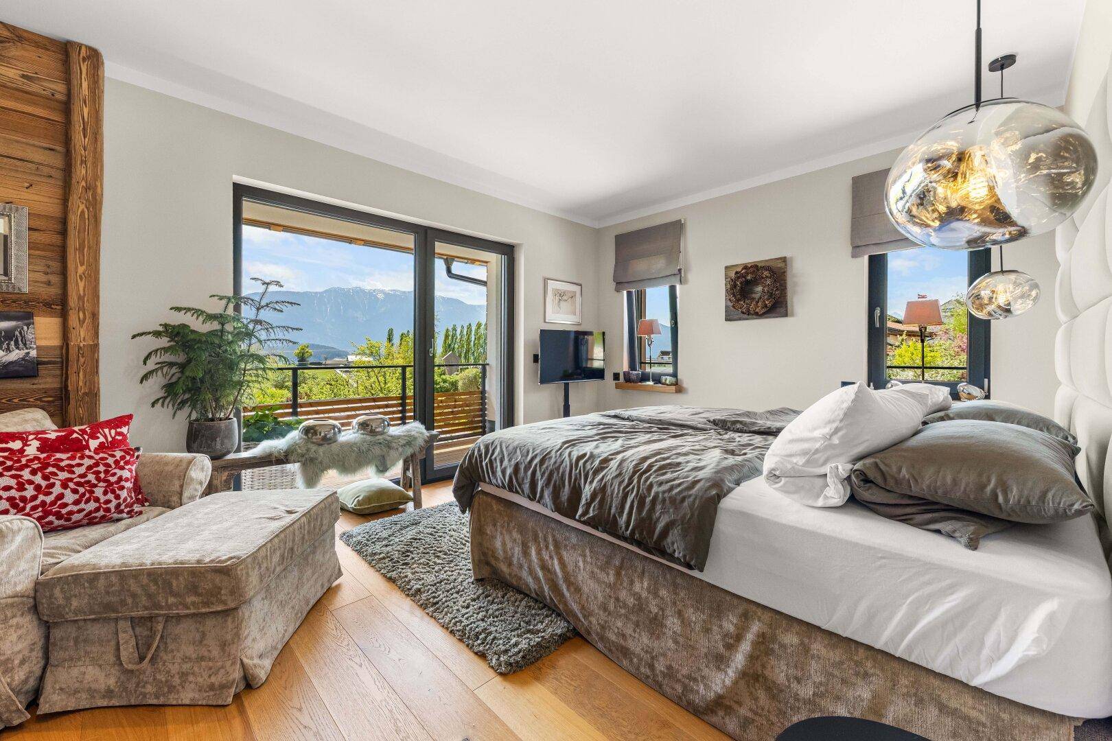 Geräumiges Schlafzimmer mit großem Bett, Holzboden und direktem Zugang zum Balkon.