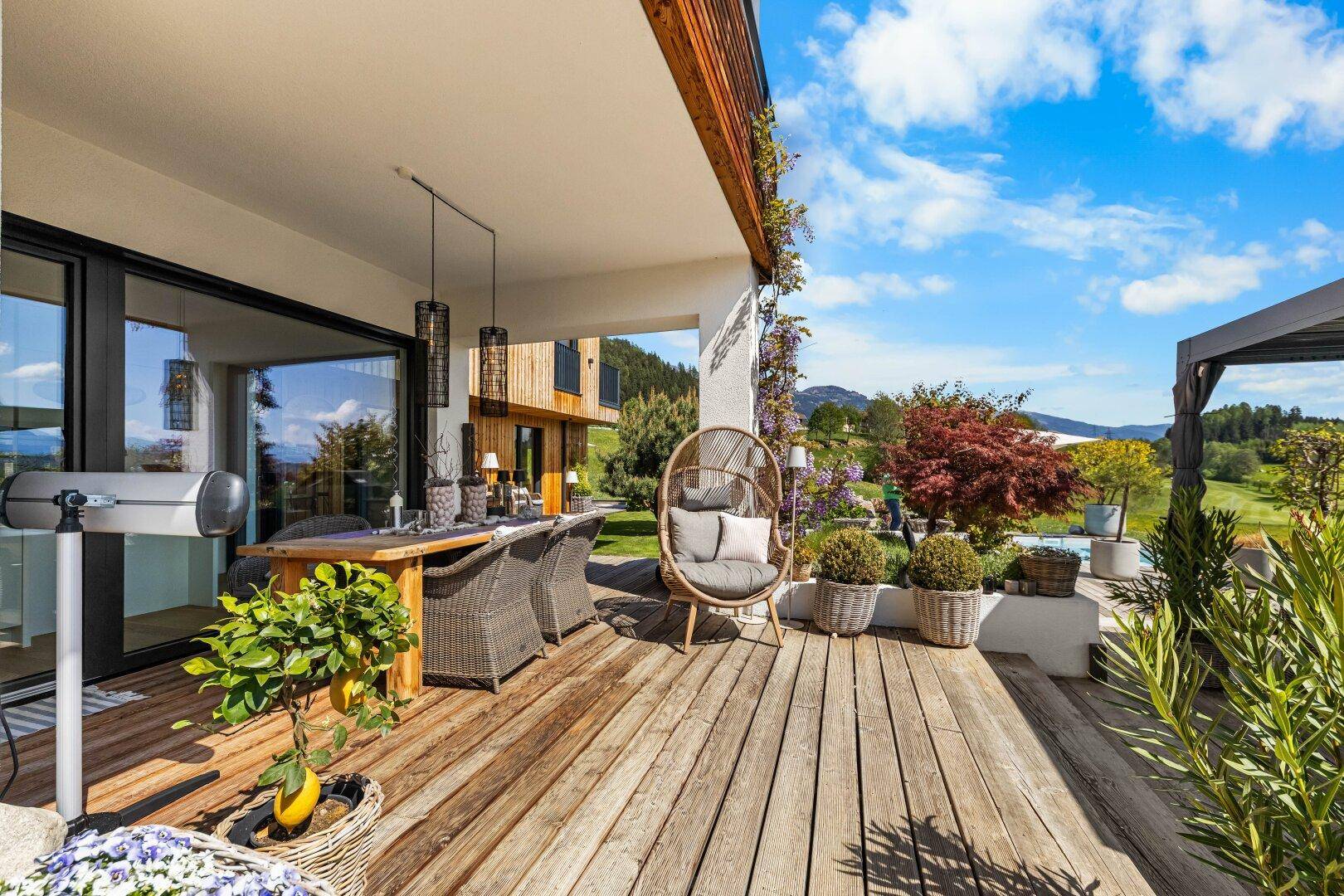 Überdachte Holzterrasse mit stilvollen Gartenmöbeln und weitem Blick in die Natur.