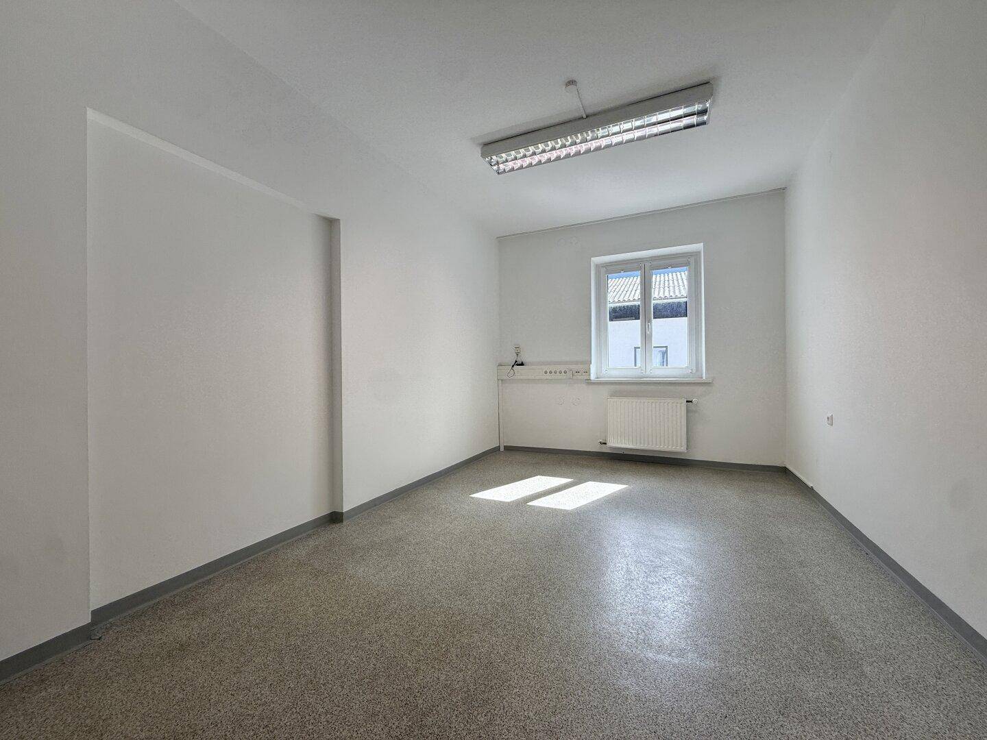 Geräumiger, heller Büroraum mit Tageslichteinfall durch das Fenster und funktionaler Ausstattung.