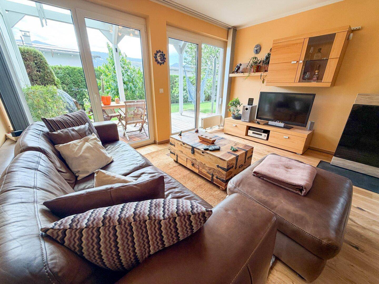 Gemütliches Wohnzimmer mit Ledersofa, Holztisch und direktem Zugang zur Terrasse.