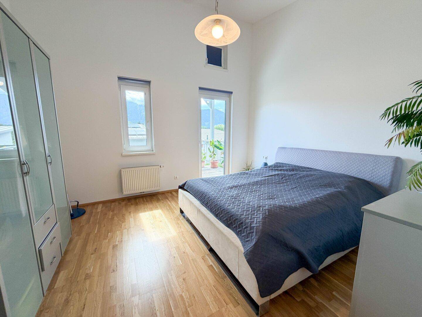 Geräumiges Schlafzimmer mit Doppelbett, Kleiderschrank und Fenstern mit Bergblick.
