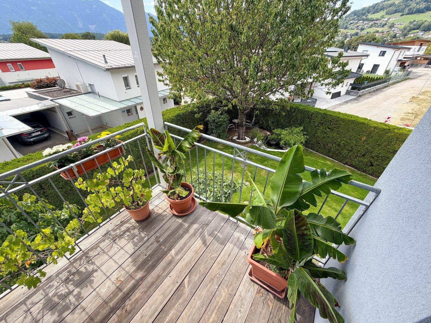 Kleiner Balkon mit Holzboden, Topfpflanzen und Blick auf die umliegende Wohngegend.