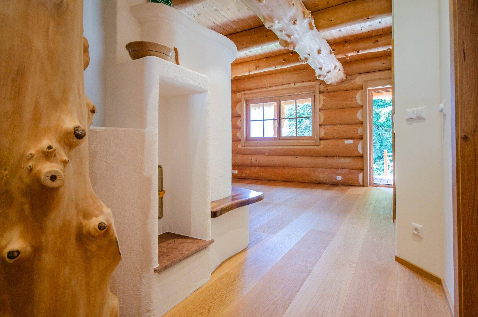 Heller Innenraum mit Holzbalken, Dielenboden und einem traditionellen Kachelofen, der Wärme spendet.
