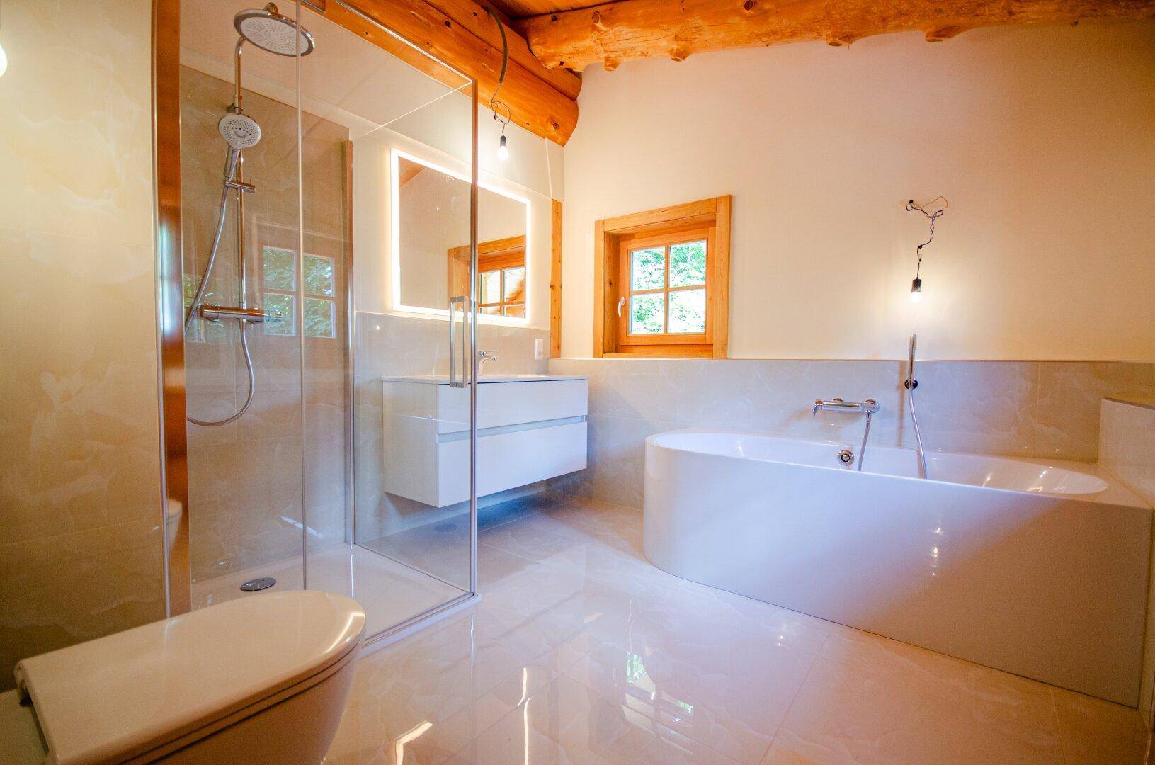 Modernes Badezimmer mit begehbarer Dusche, freistehender Badewanne und eleganten Fliesen, unter Holzbalken.