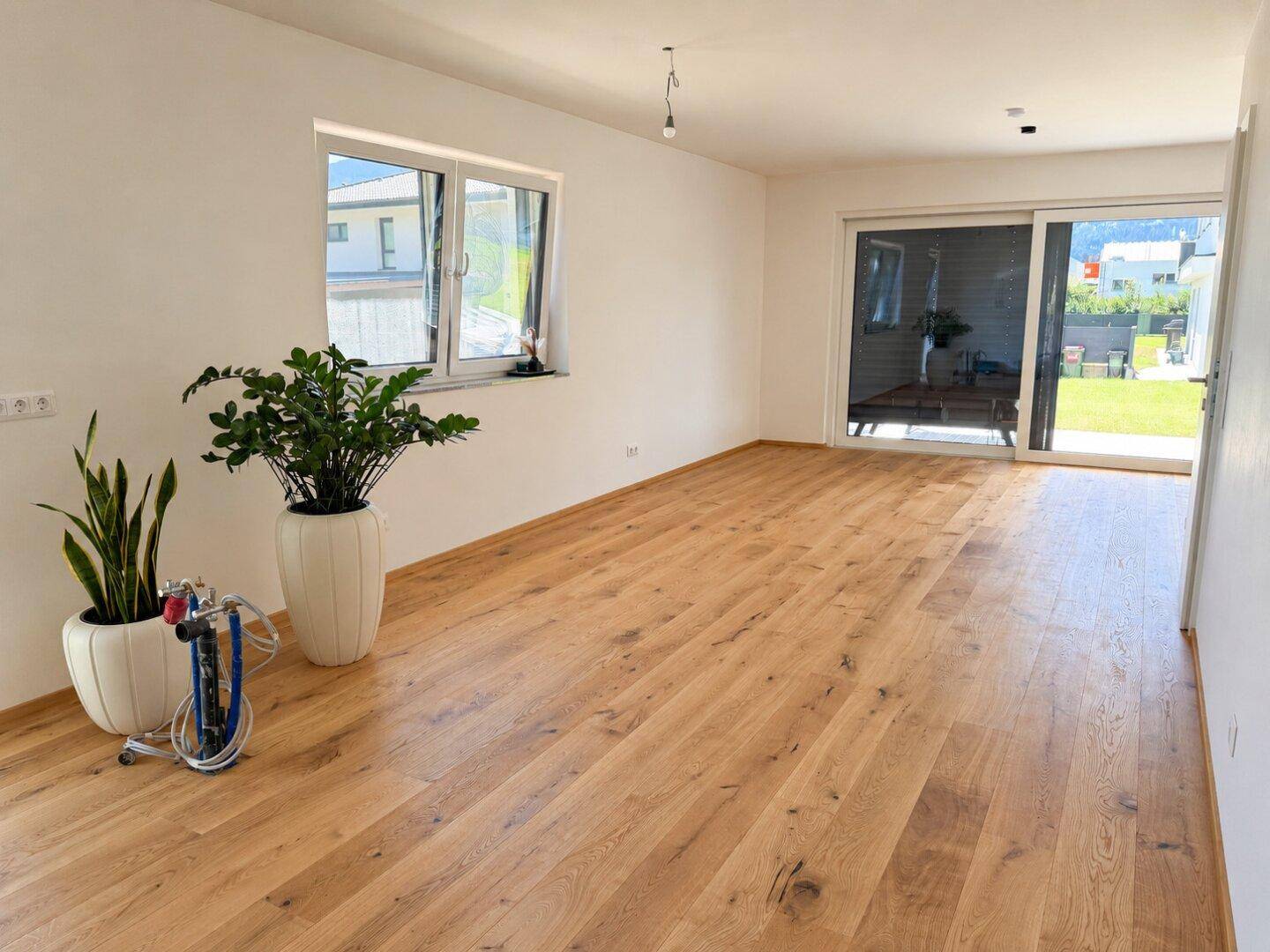 Geräumiges Wohnzimmer mit Eichenparkett und Schiebetür zum Garten.