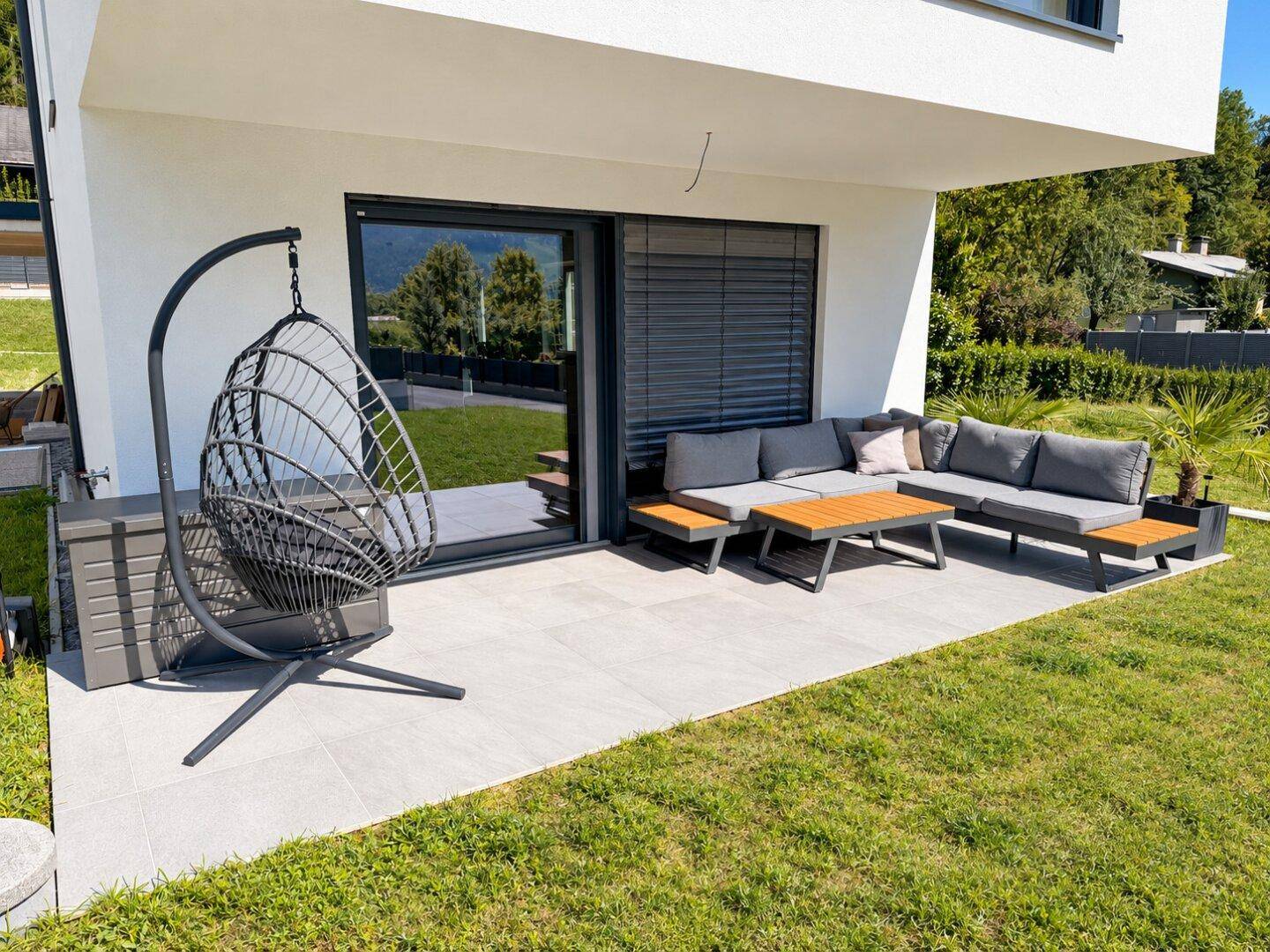 Gemütliche Terrasse mit modernen Gartenmöbeln und Blick auf den grünen Garten.