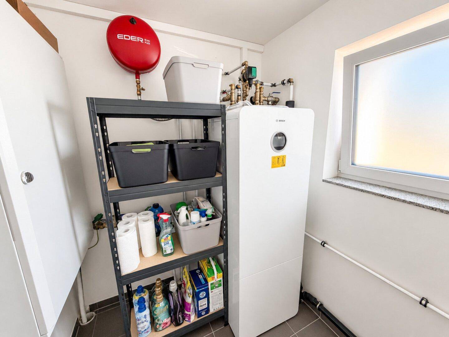 Praktischer Hauswirtschaftsraum mit Wärmepumpe, Regalen und Fenster.
