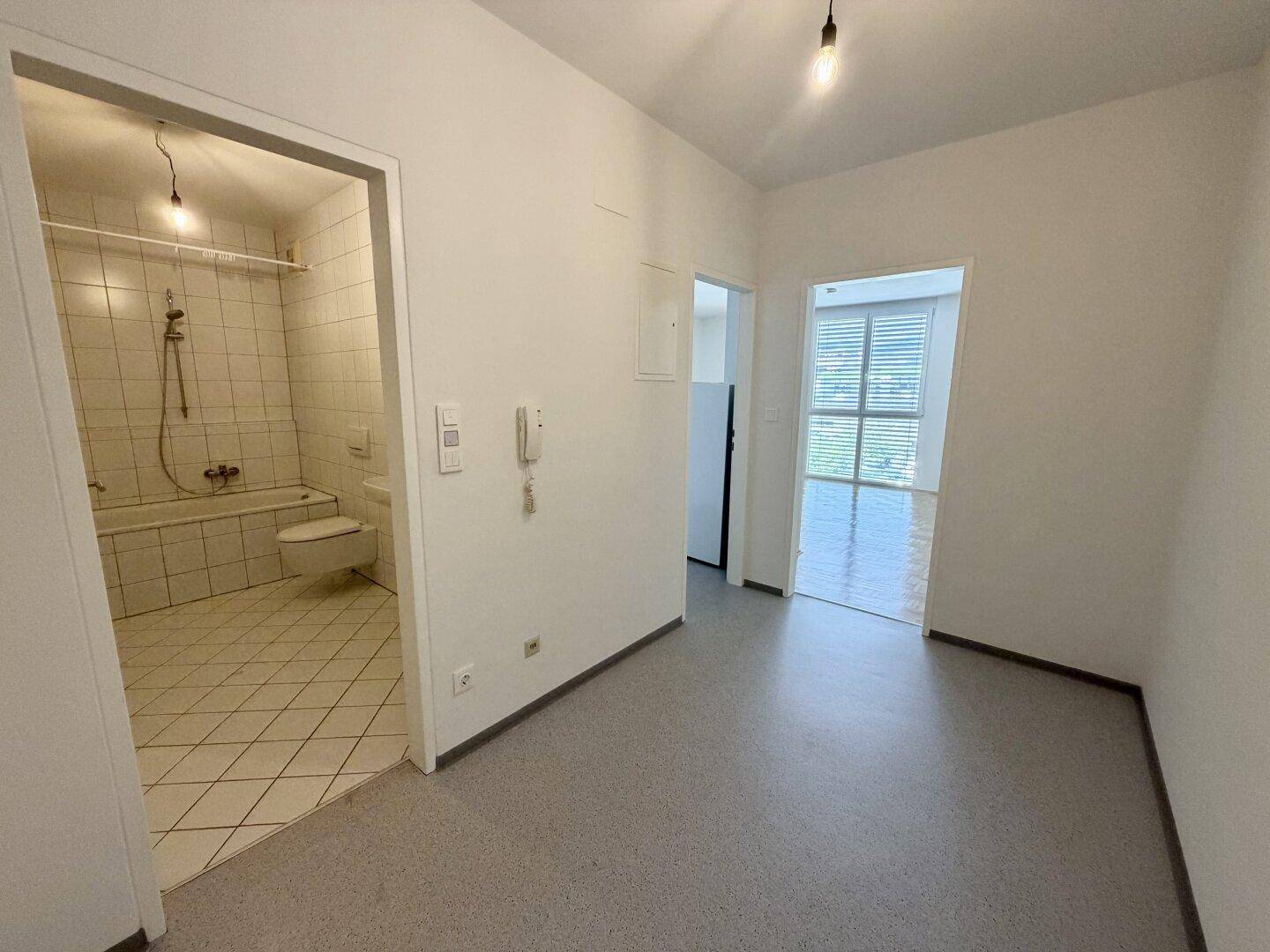 Flur mit Zugang zum Badezimmer und einem weiteren Zimmer, ausgestattet mit Vinylboden.