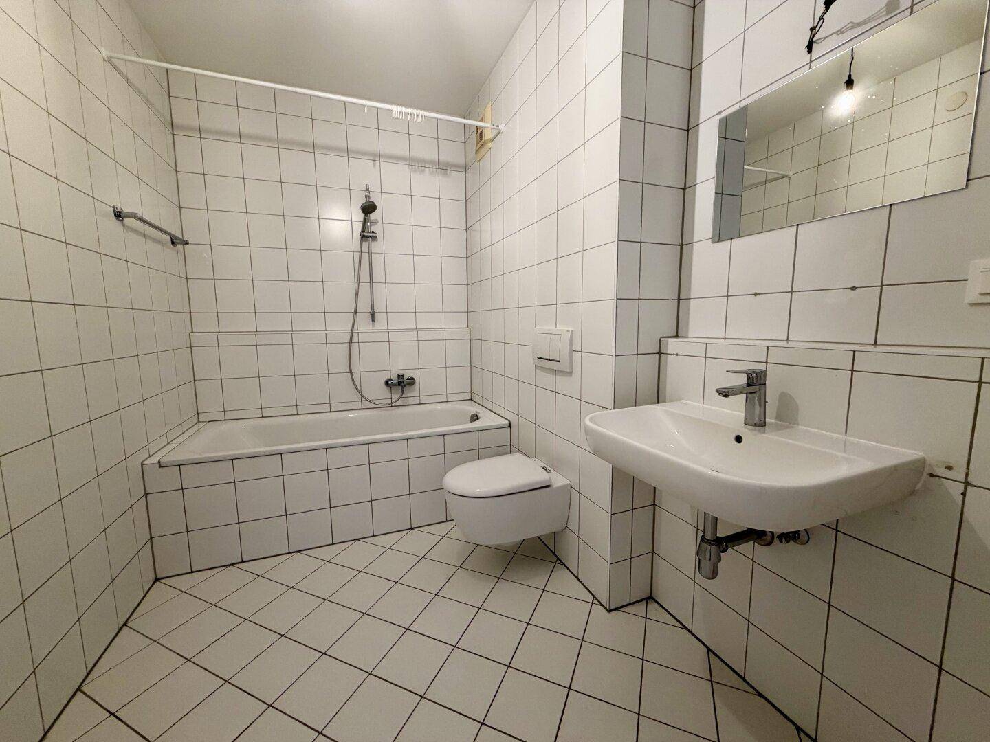 Gefliestes Badezimmer mit Badewanne, Toilette und Waschbecken in klassischem Design.