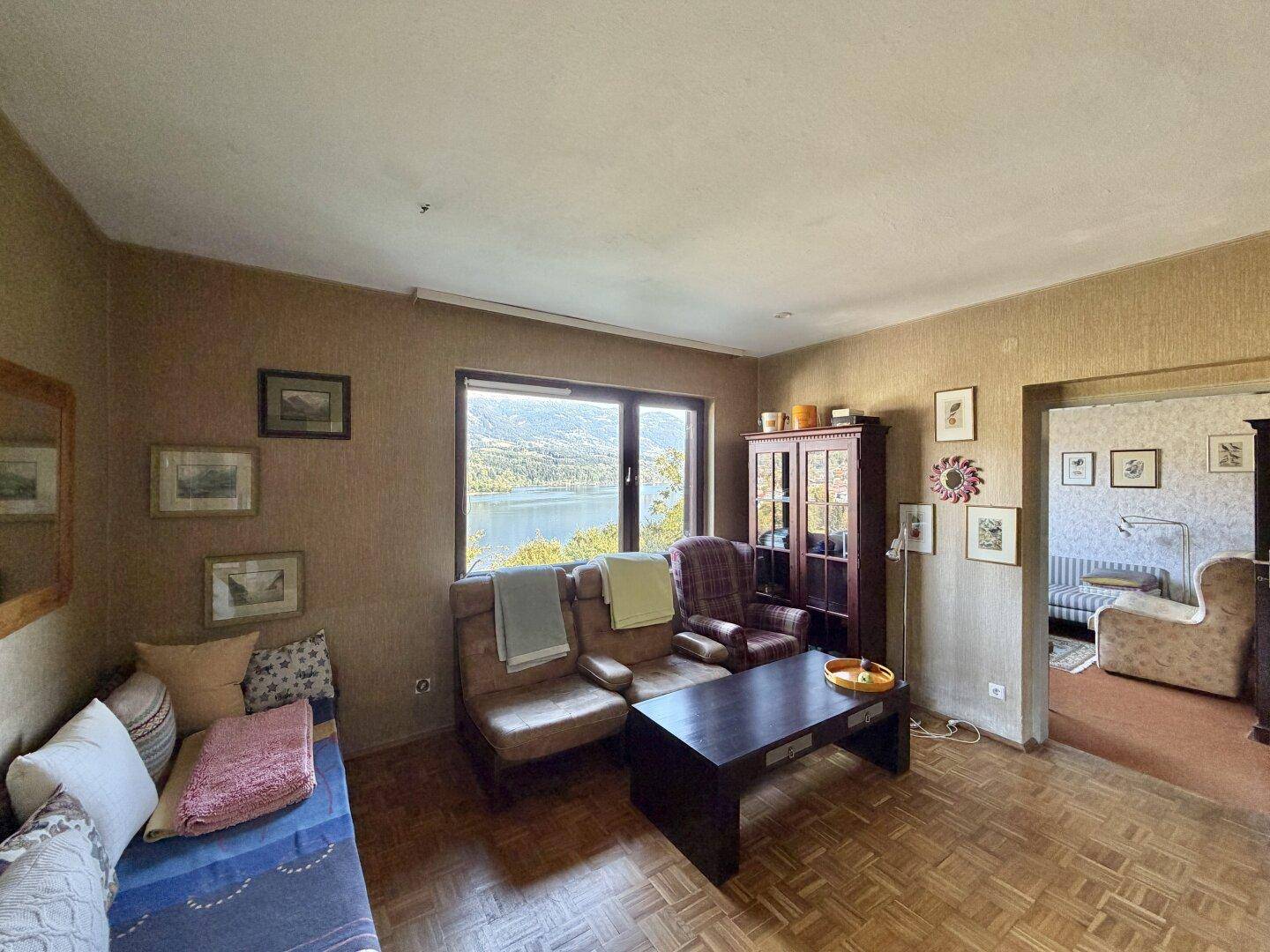 Wohnzimmer mit Seeblick, bequemen Sitzgelegenheiten und traditioneller Einrichtung.