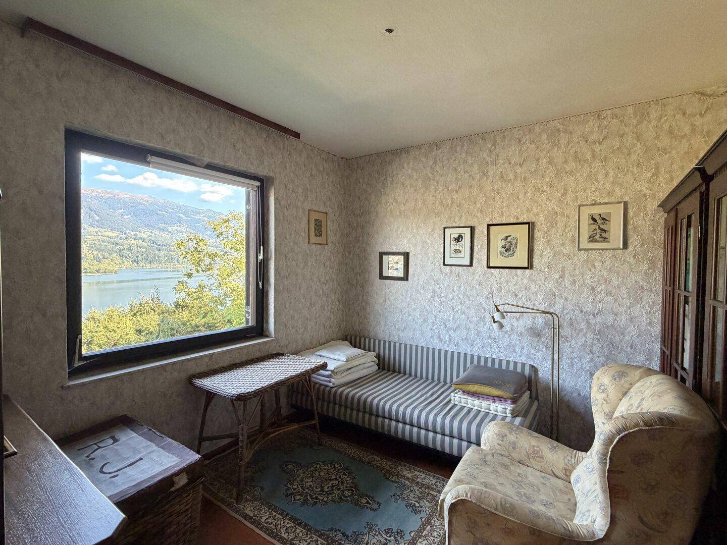 Schlafzimmer mit Seeblick, Tagesbett und traditionellem Teppichboden.