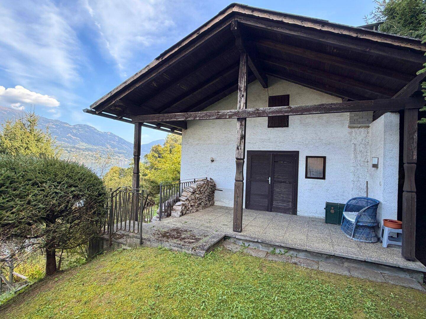 Überdachte Terrasse am Haus mit Holzbalken, Sitzgelegenheit und Bergblick.