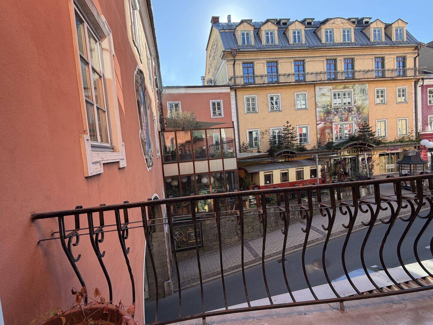 Blick von einem Balkon mit schmiedeeisernem Geländer auf die umliegenden Gebäude der Stadt.