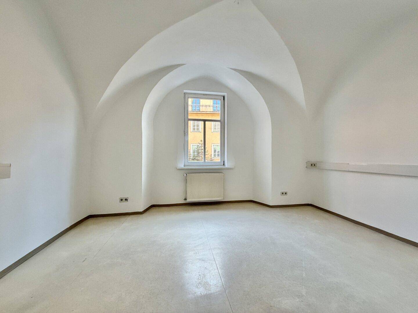 Raum mit beeindruckendem Gewölbedecke, hellem Boden und einem Fenster, das den Innenhof überblickt.