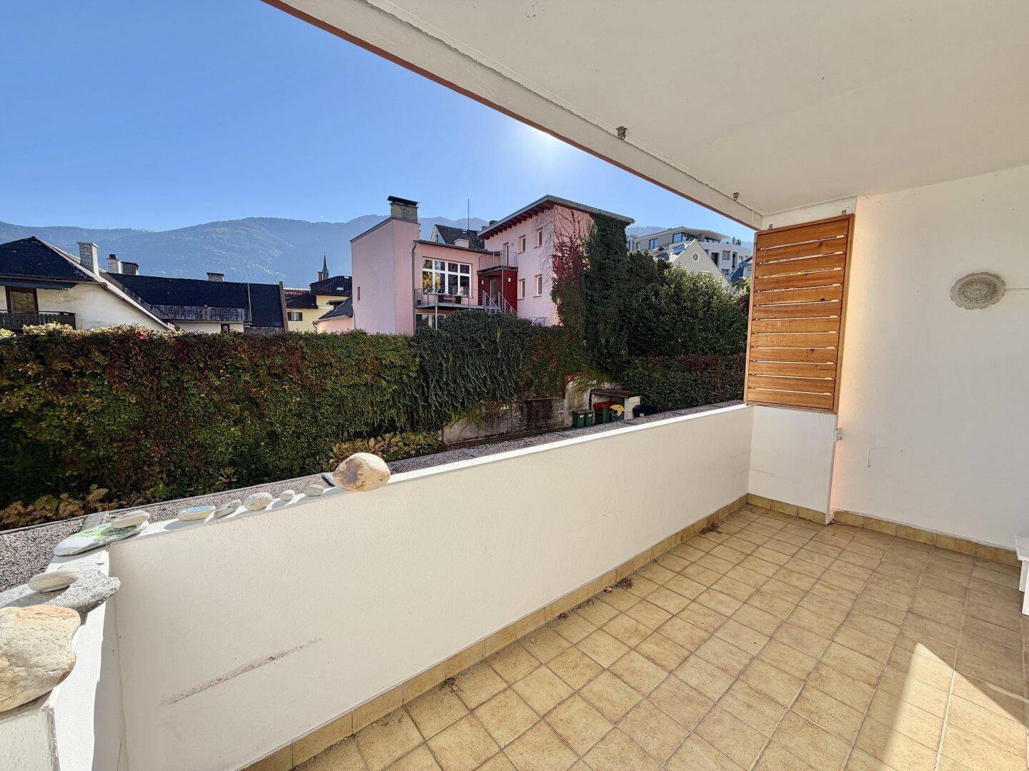 Sonniger Balkon mit Fliesenboden und weitem Blick auf die Berge und Nachbarschaft.