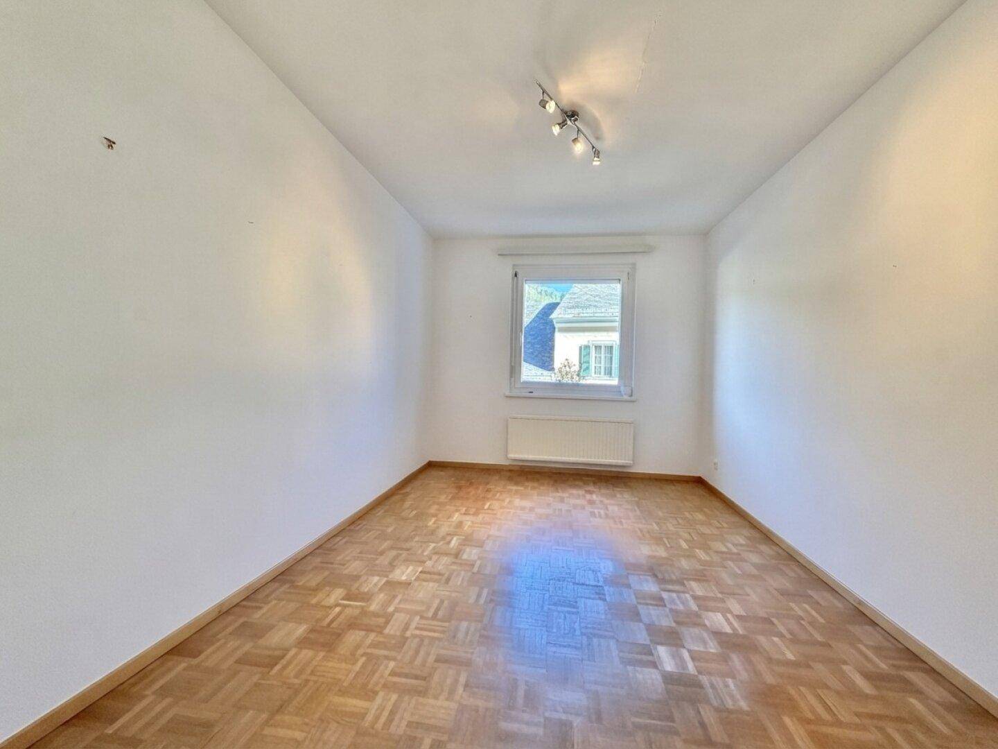 Kleiner Raum mit Parkettboden und einem Fenster, ideal als Schlaf- oder Arbeitszimmer.
