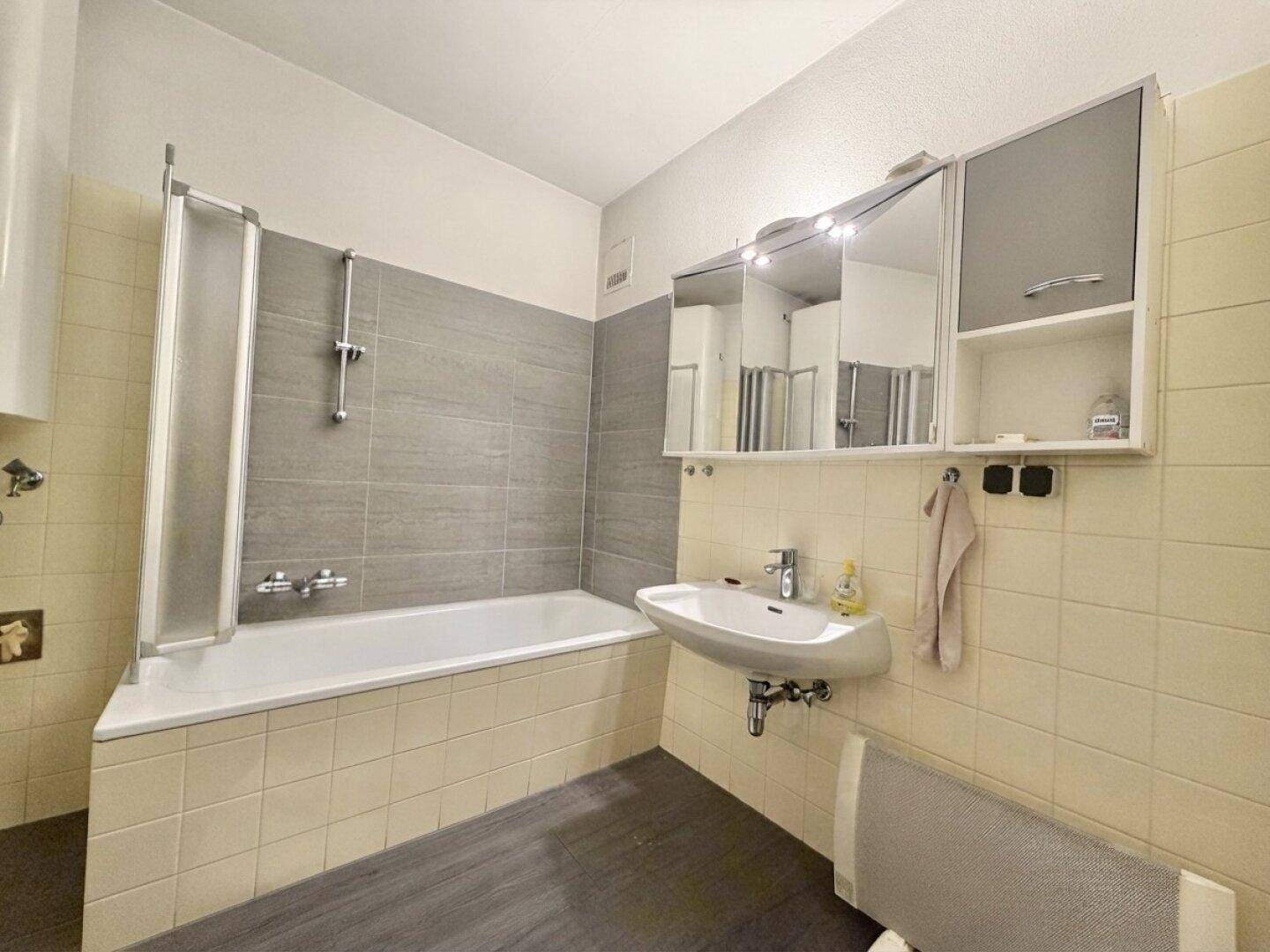 Badezimmer mit Badewanne, Duschvorrichtung und einem einzelnen Waschbecken.