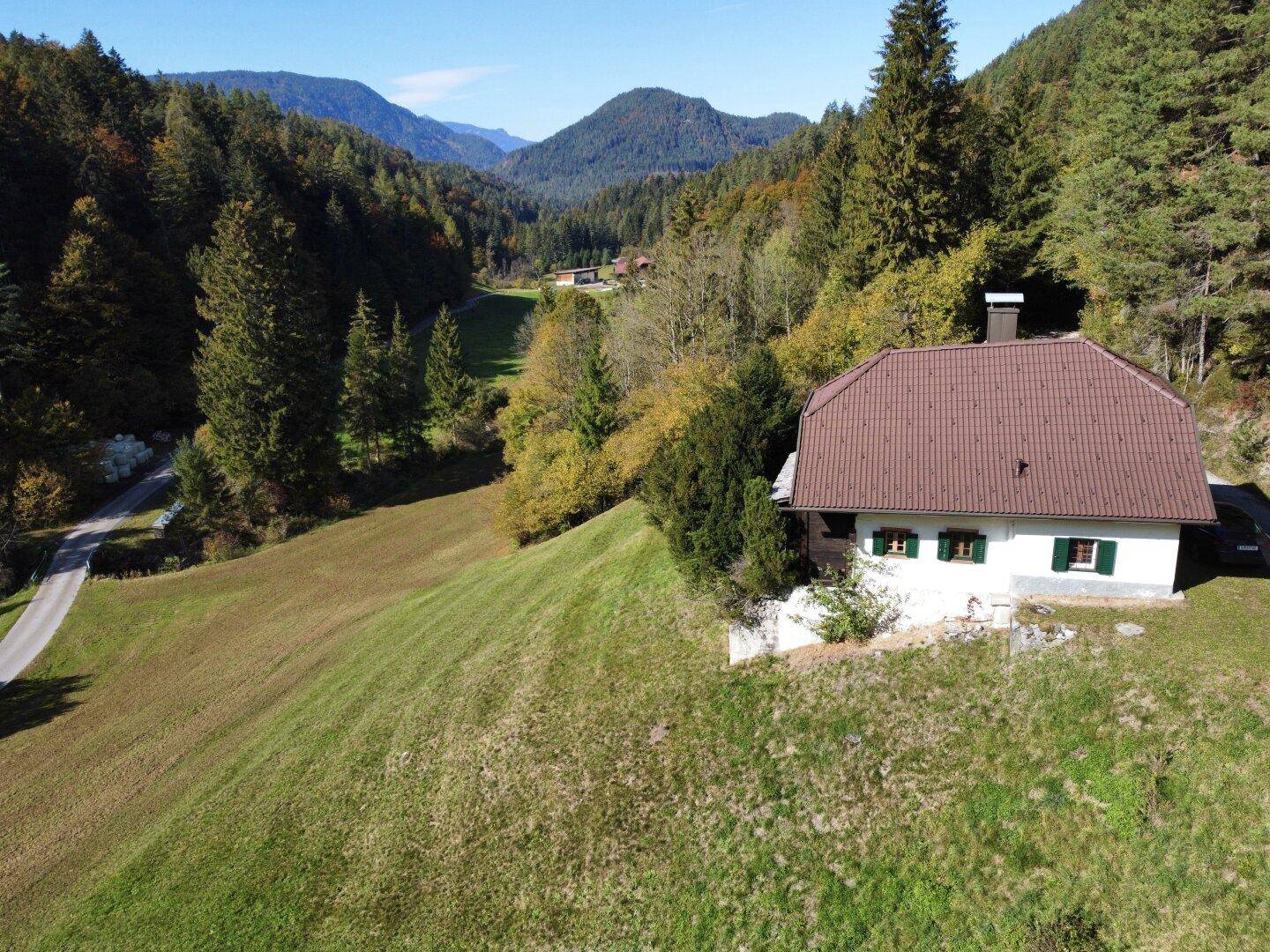 Weitläufige Ansicht des Hauses in einer idyllischen Berglandschaft mit viel Grün.