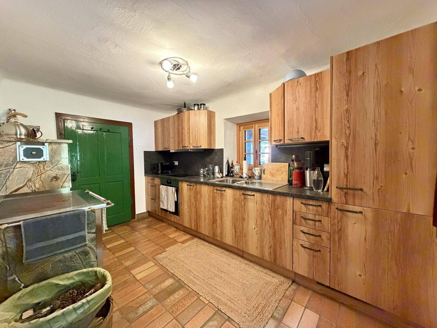 Rustikale Küche mit Holzschränken, Terrakottafliesen und traditionellem Holzofen.