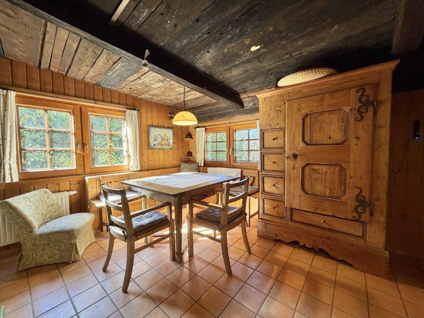 Gemütlicher Essbereich mit Holztäfelung, rustikalen Möbeln und Terrakottafliesen.