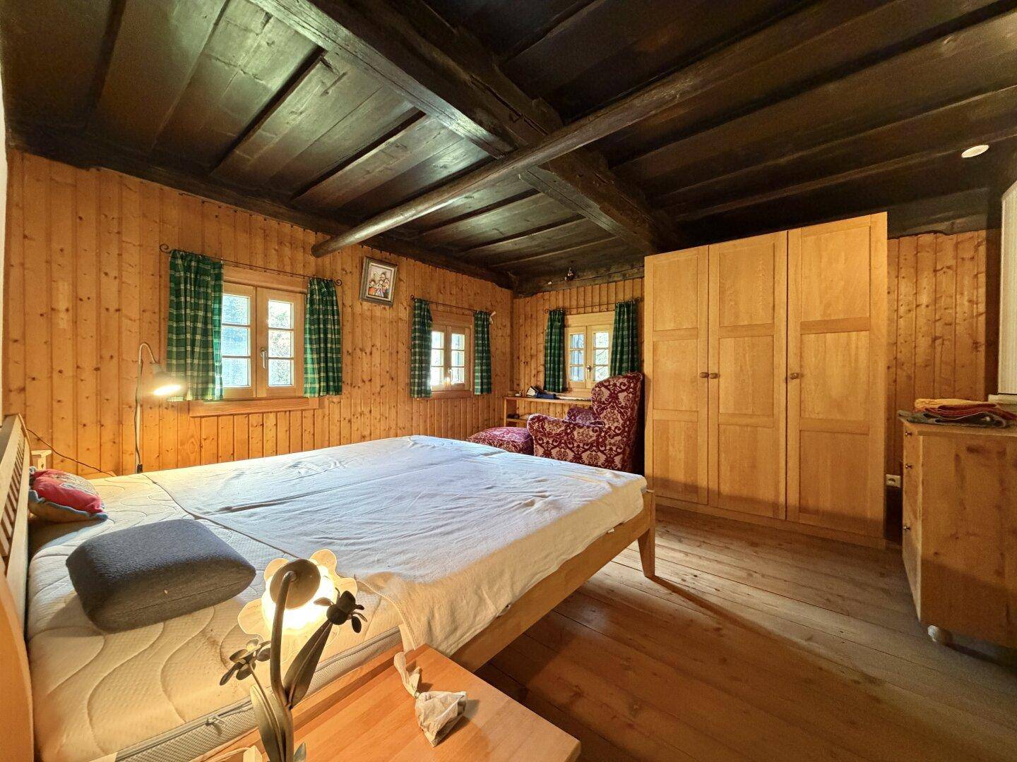Schlafzimmer im alpinen Stil mit Holzwänden, Holzboden und traditionellen Holzmöbeln.