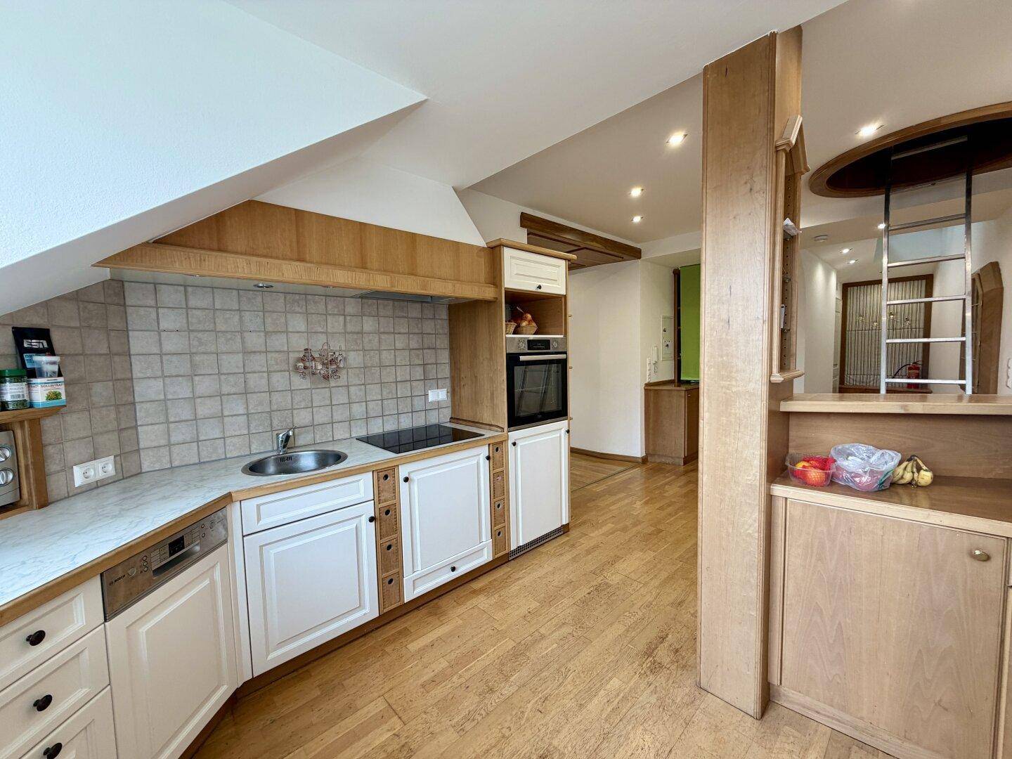 Gemütliche Einbauküche mit hellen Fronten, Holzdetails, Fliesenrückwand und integrierten Geräten.