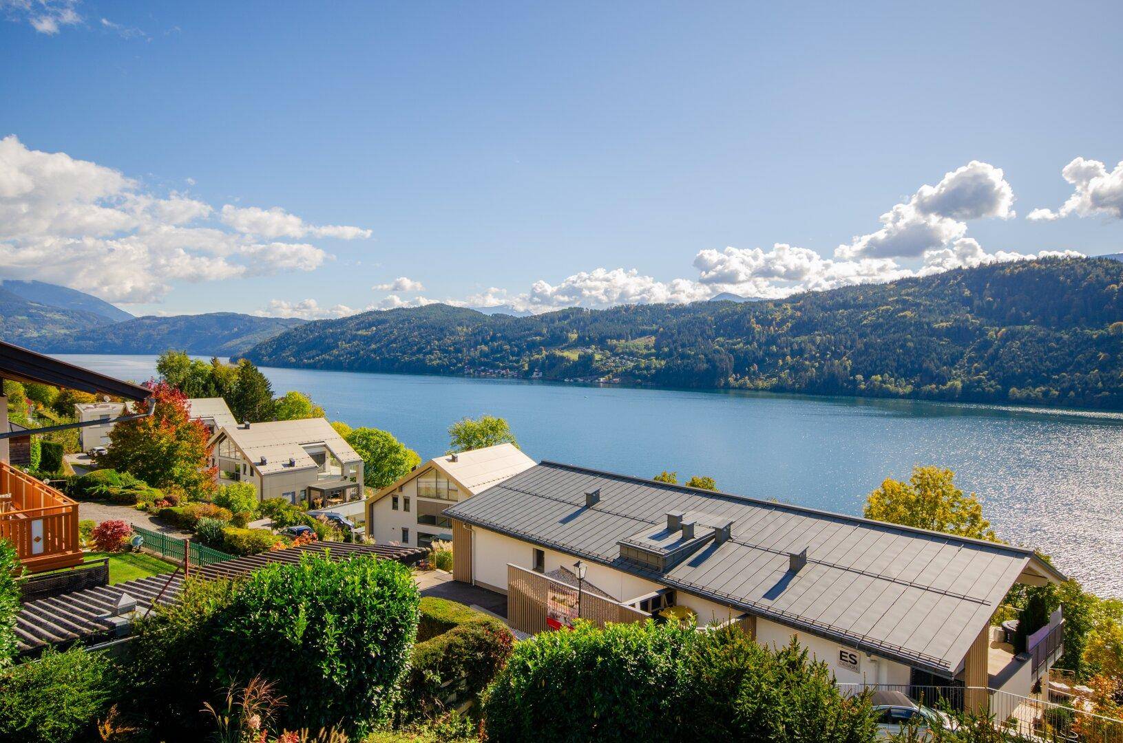 Panoramablick auf die moderne Wohnanlage am Seeufer mit umliegender grüner Landschaft.